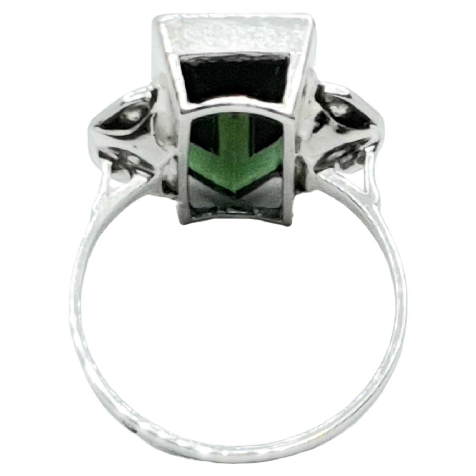 Antique green tourmaline white gold ring. The center green stone is oblong shape  and very vibrant color. Small old diamonds are set on both sides.  This French origin ring is unique looking.
The tourmaline size:13mmx6mm