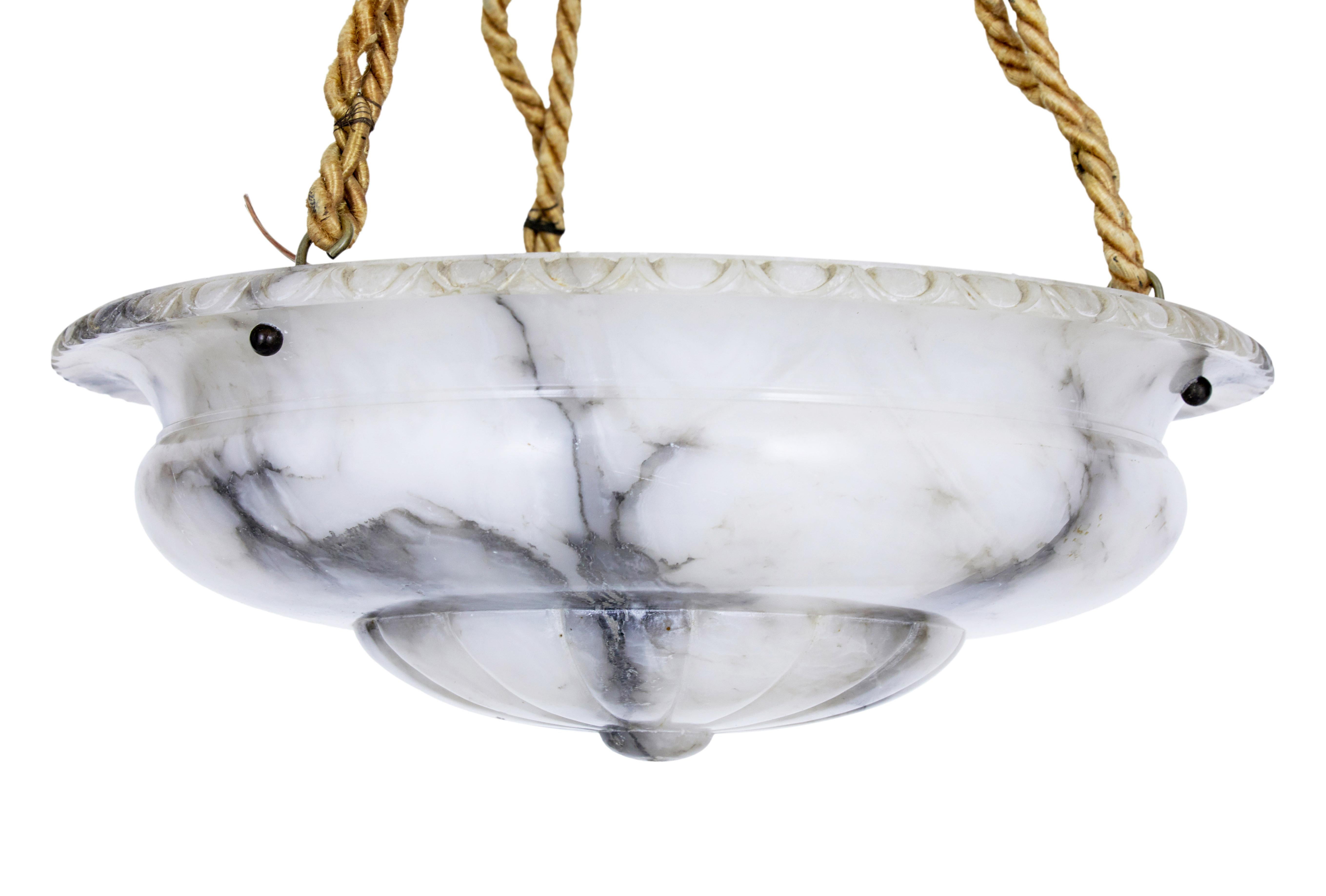 Art Deco grey alabaster hanging dish light circa 1930.

Beautiful grey veined carved alabaster chandelier from the Art Deco period. Carved alabaster bowl with carved rim, supported by 3 rope chains, leading up to a steel covered ceiling