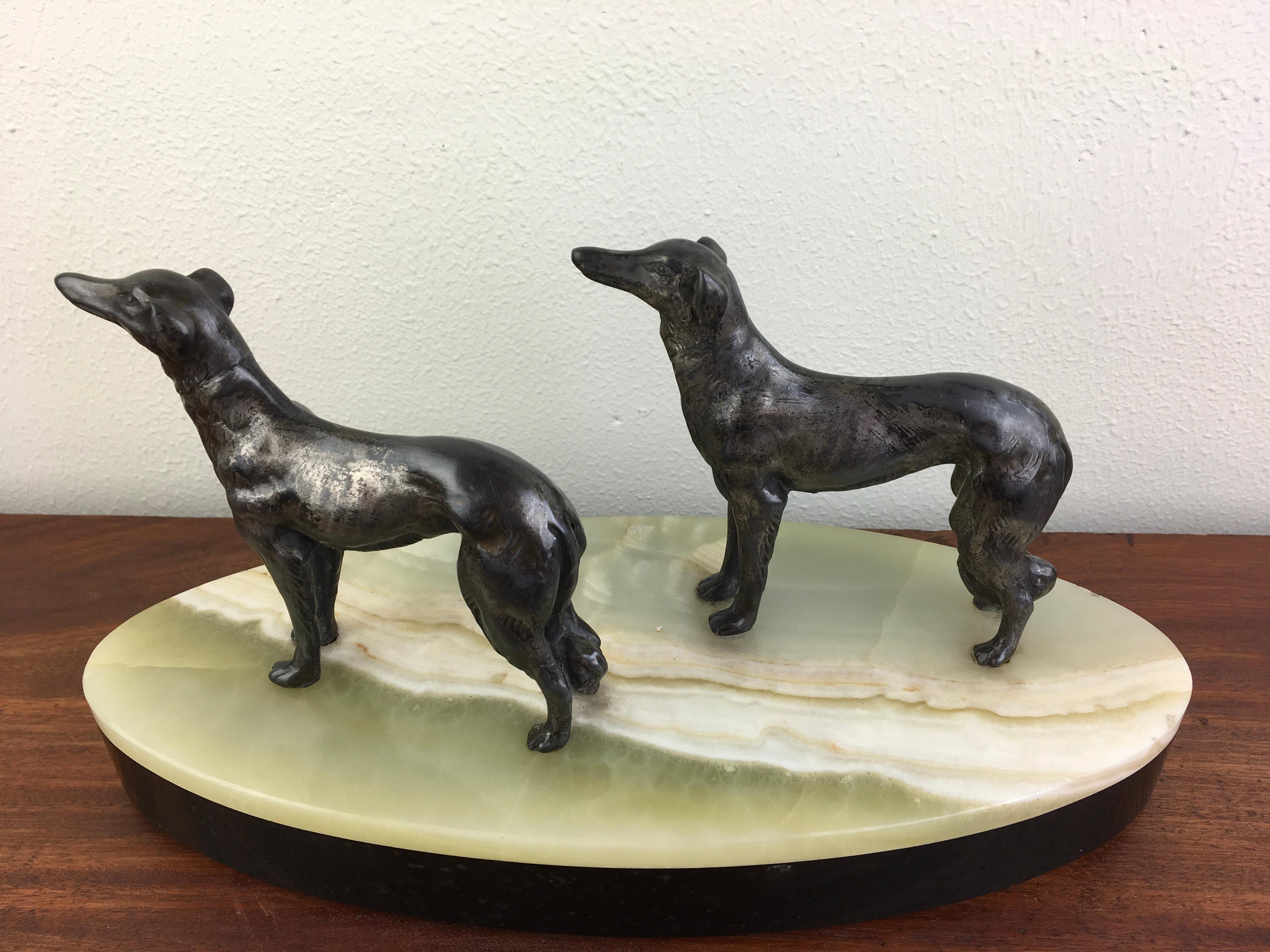 Art Deco group of greyhounds - Whipped dogs mounted on a oval marble base. 
This two spelter dog figurines look fine on the two toned marble base. 
It's a stylish statue - desk ornament for a dog lover - greyhound lover.