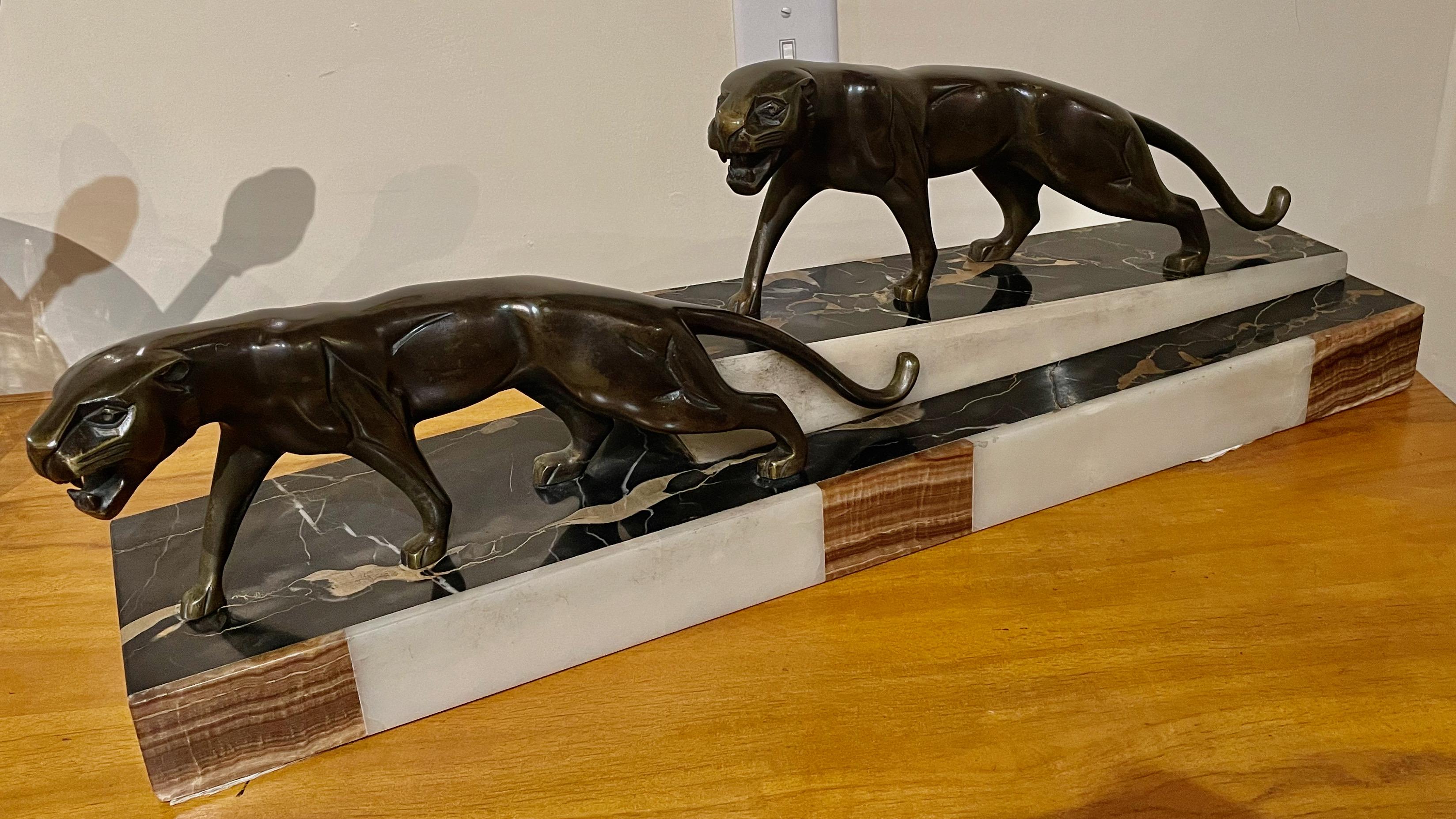 Wunderschöne Art-Déco-Bronzegruppe mit zwei Panthern von dem französischen Künstler Dominique Jean Baptiste Hugues. Die Skulptur hat eine schöne Patina und steht auf einem Sockel aus Portoro-Marmor mit Onyxeinlage, Frankreich 1930. Der Künstler ist