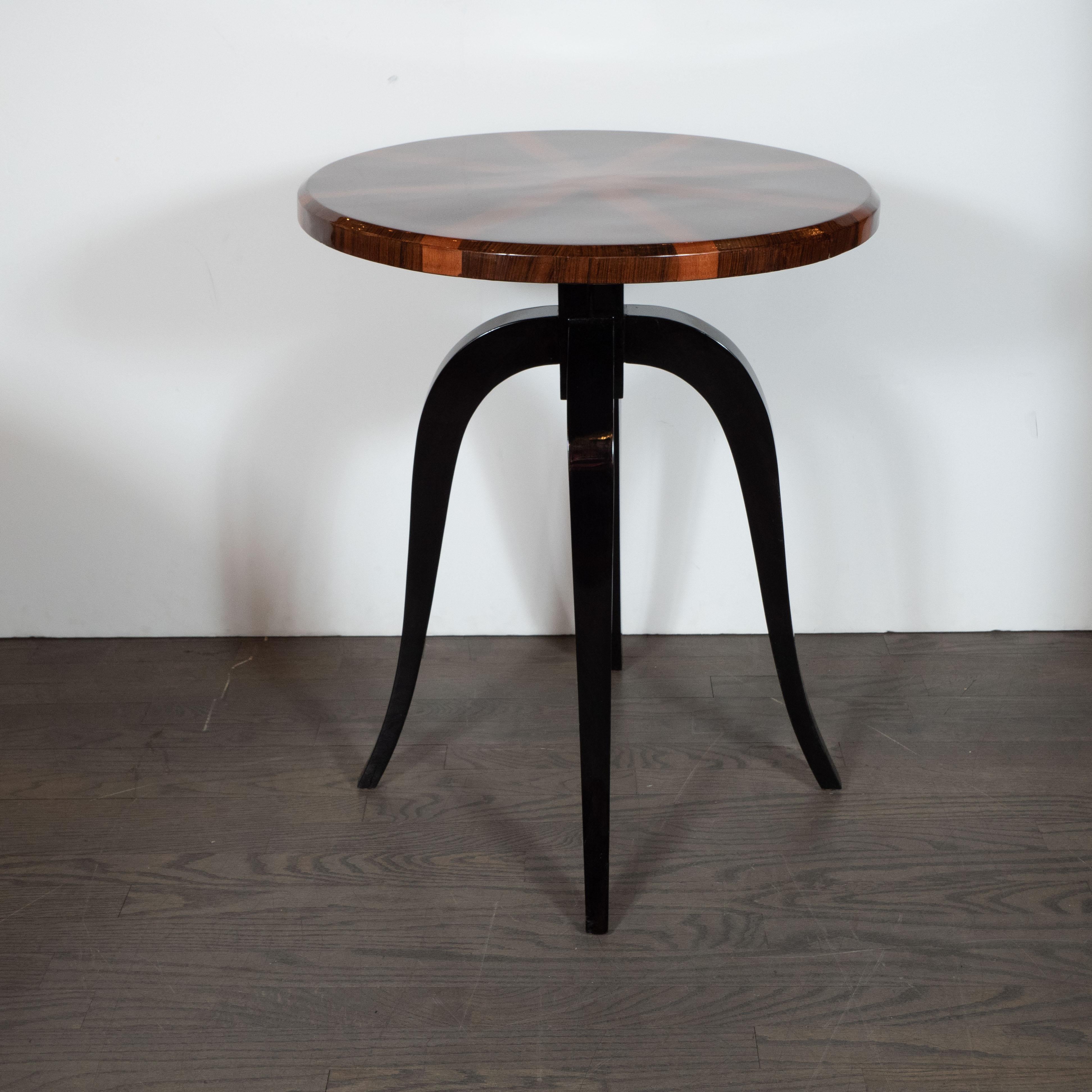 This sophisticated and dramatic Gueridon table was realized in France, circa 1930. Supported by four curvilinear legs in ebonized walnut, the table offers a round top composed of walnut and carpathian elm bookmatched to create a stunning starburst