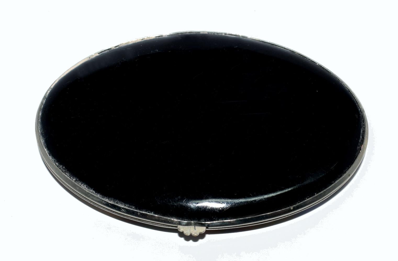 A delightful ladies Art Deco compact marked to the interior with the trade name Gwenda 'Tap flap' made in England with the registration design number for 1931. The back is black enamel with the lid depicting a wonderful romantic scene of a young