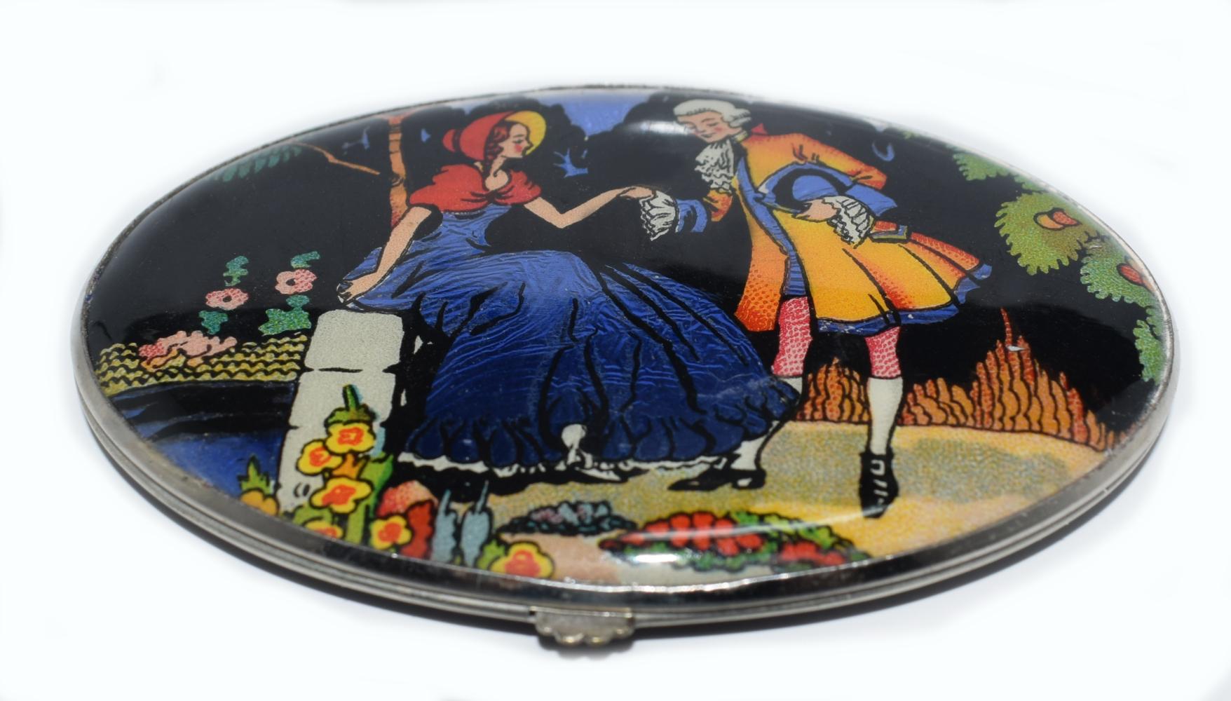 A delightful ladies Art Deco compact marked to the interior with the trade name Gwenda 'Tap flap' made in England with the registration design number for 1931. The back is black enamel with the lid depicting a wonderful romantic scene of a young