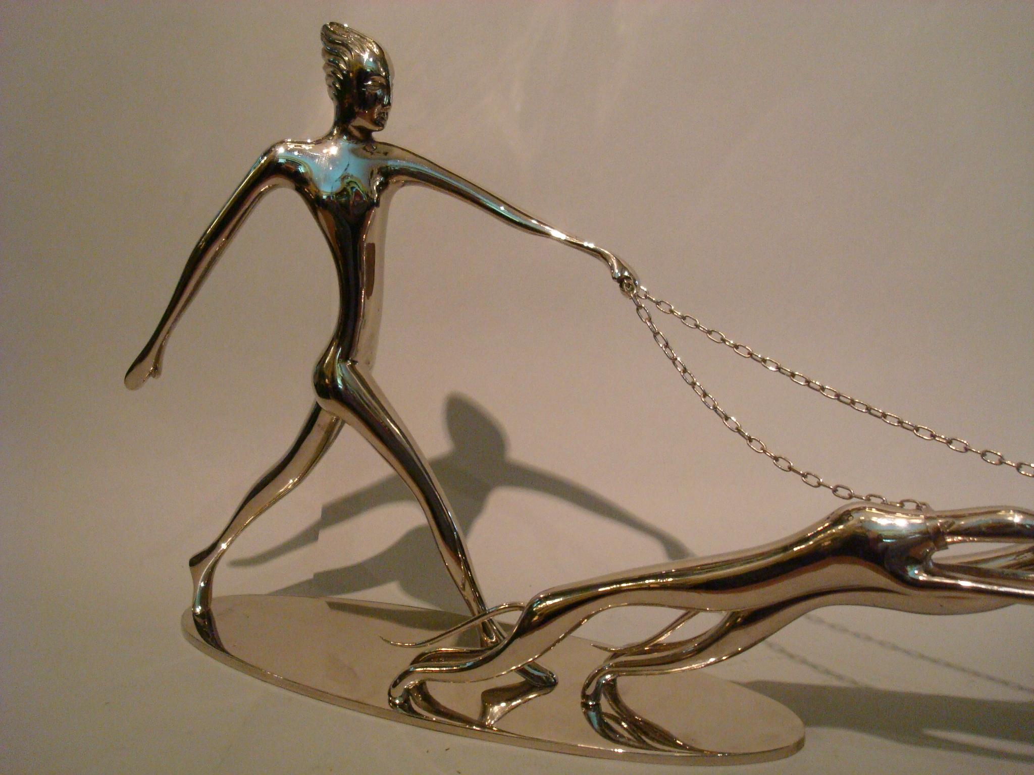 This dynamic sculpture was designed by Austrian sculptor Karl Hagenauer, known for his iconic Art Deco decorative objects and furniture designs. This piece is composed of nickel-plated brass and features the highly stylized image of a woman, the