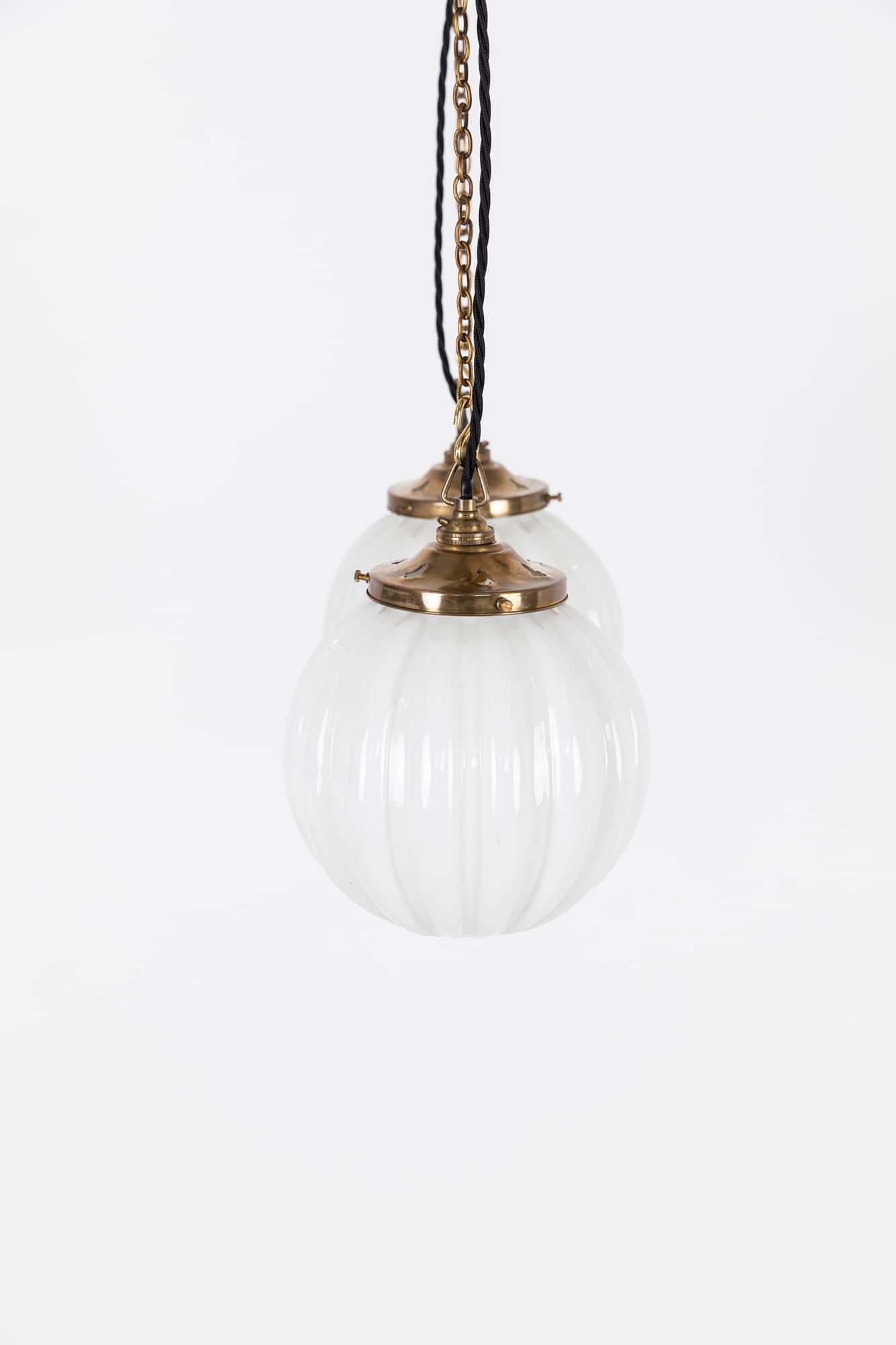 

An elegant pair of spheprical opaline pendant lamps made in England by Hailware. c.1930

Pressed glass with a deep ribbed design. Faintly stamped 'Hailware' to the top of the glass. Complementing and period brass gallery. Price is per