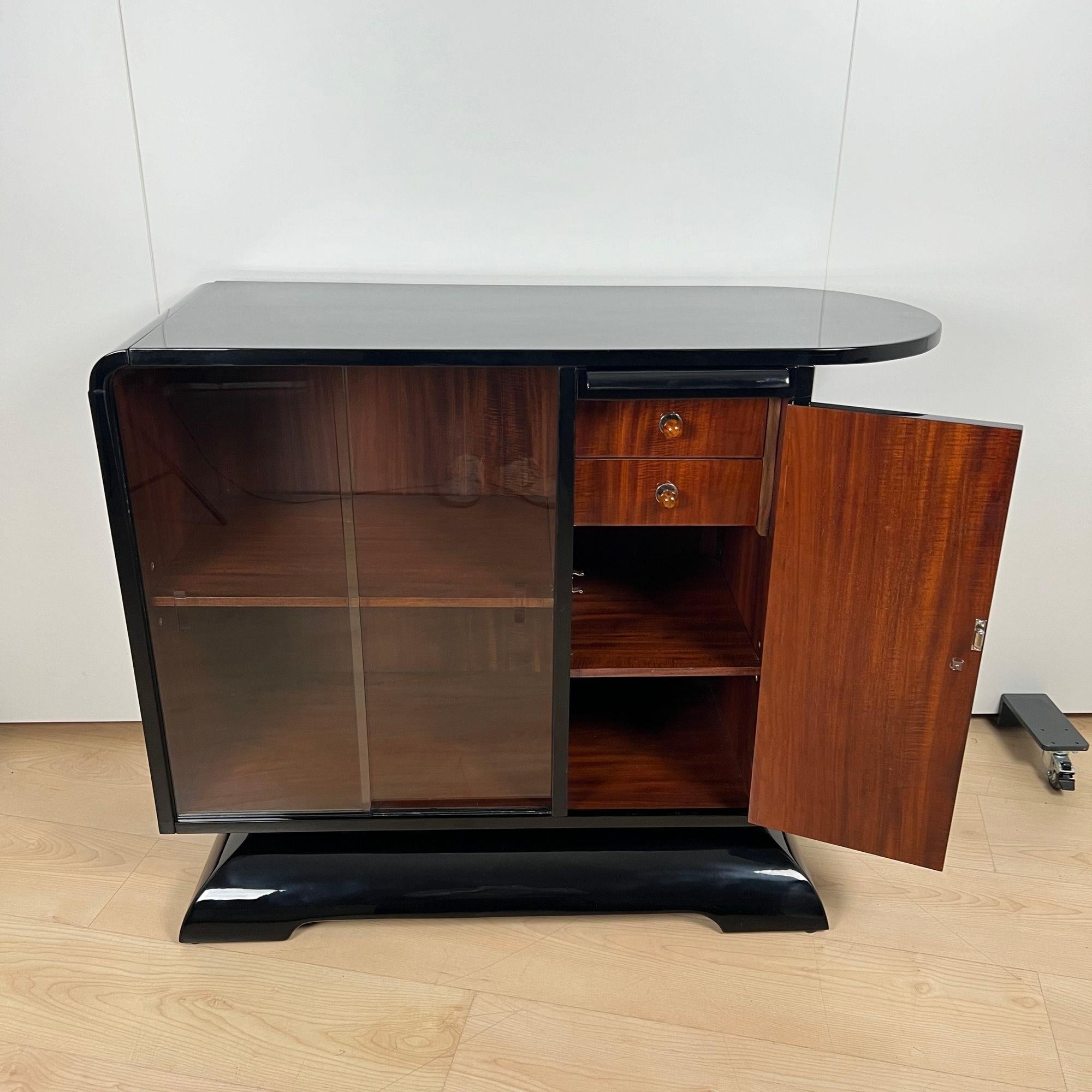 Magnifique demi-meuble ou petit meuble de bar Art Déco d'origine française vers 1930.
Entièrement restauré avec une laque piano noire brillante. Design/One avec des étagères rondes sur les côtés. Elle repose sur une base élégamment incurvée.
À