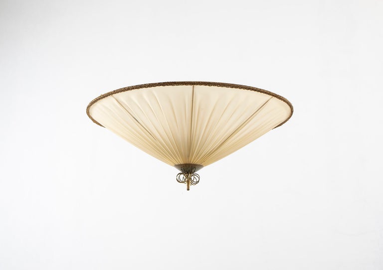Wonderful, rare, and decorative ceiling lamp in brass, nylon shade, and painted steel. Early model with the first logo, designed and made in Norway by Arne Wiig's Fabrikker from circa 1930s second half. The lamp is fully working and in fair good