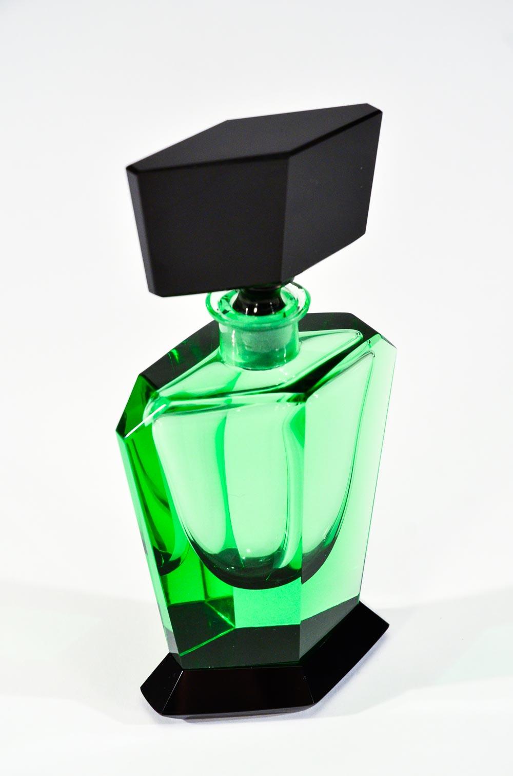 This unusually shaped Art Deco hand blown crystal perfume bottle features the vibrant contrast of rich apple green with a highly polished black stopper and foot. The base is 6 sided and the stopper is also 6 sided with subtle small angles. This