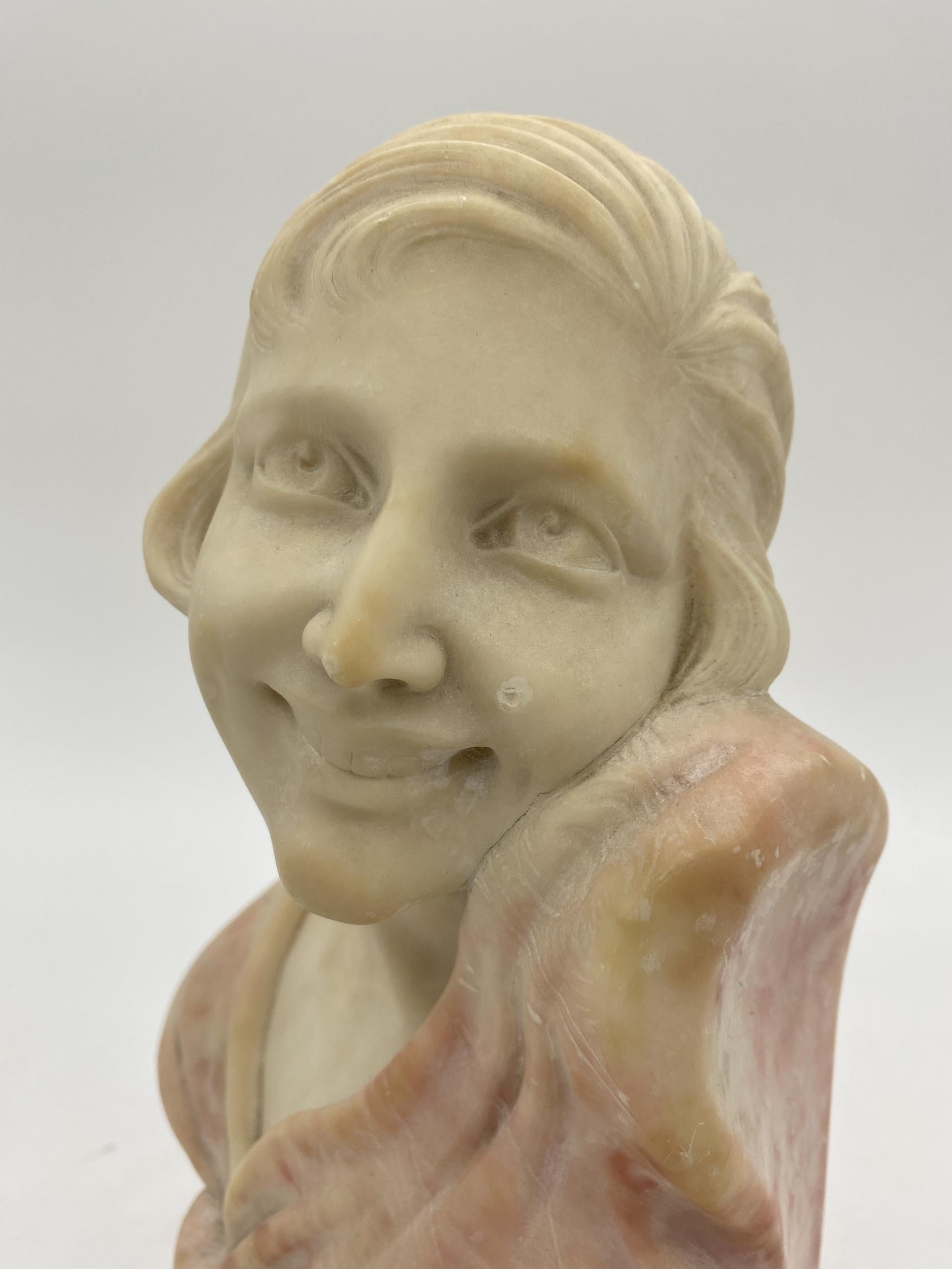 Original hand carved Art Deco bust of a young smiling Flapper woman. Worked out of Fine alabaster the sculptor has a two-tone look with the woman carved in white alabaster and her clothing carved in red alabaster. There is a great amount of detail