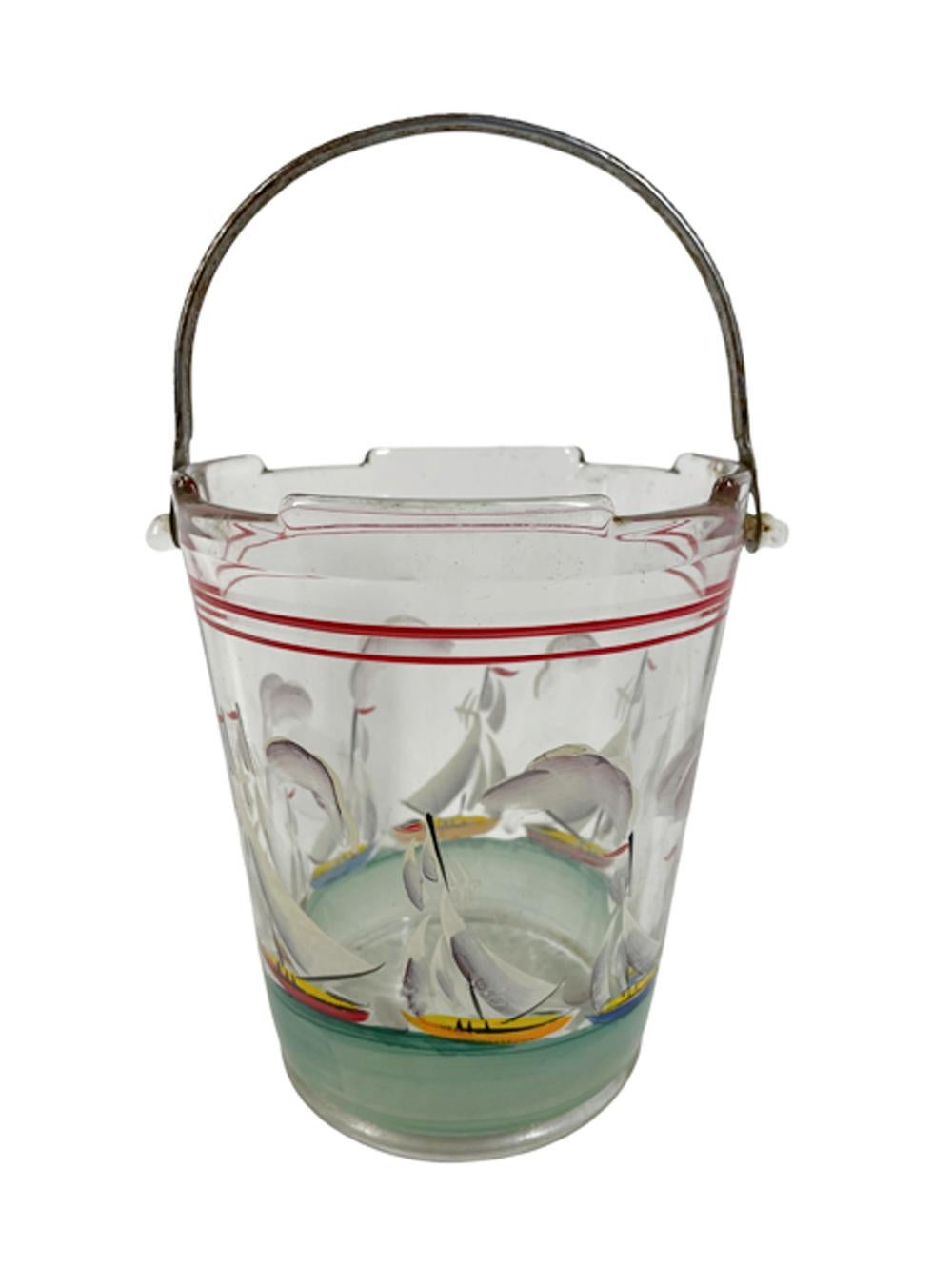 Art Deco clear glass ice bucket of pail form with a shaped rim and sunburst molded base and hammered metal swing handle hand painted with clouds above a variety of sailboats on a green sea.
