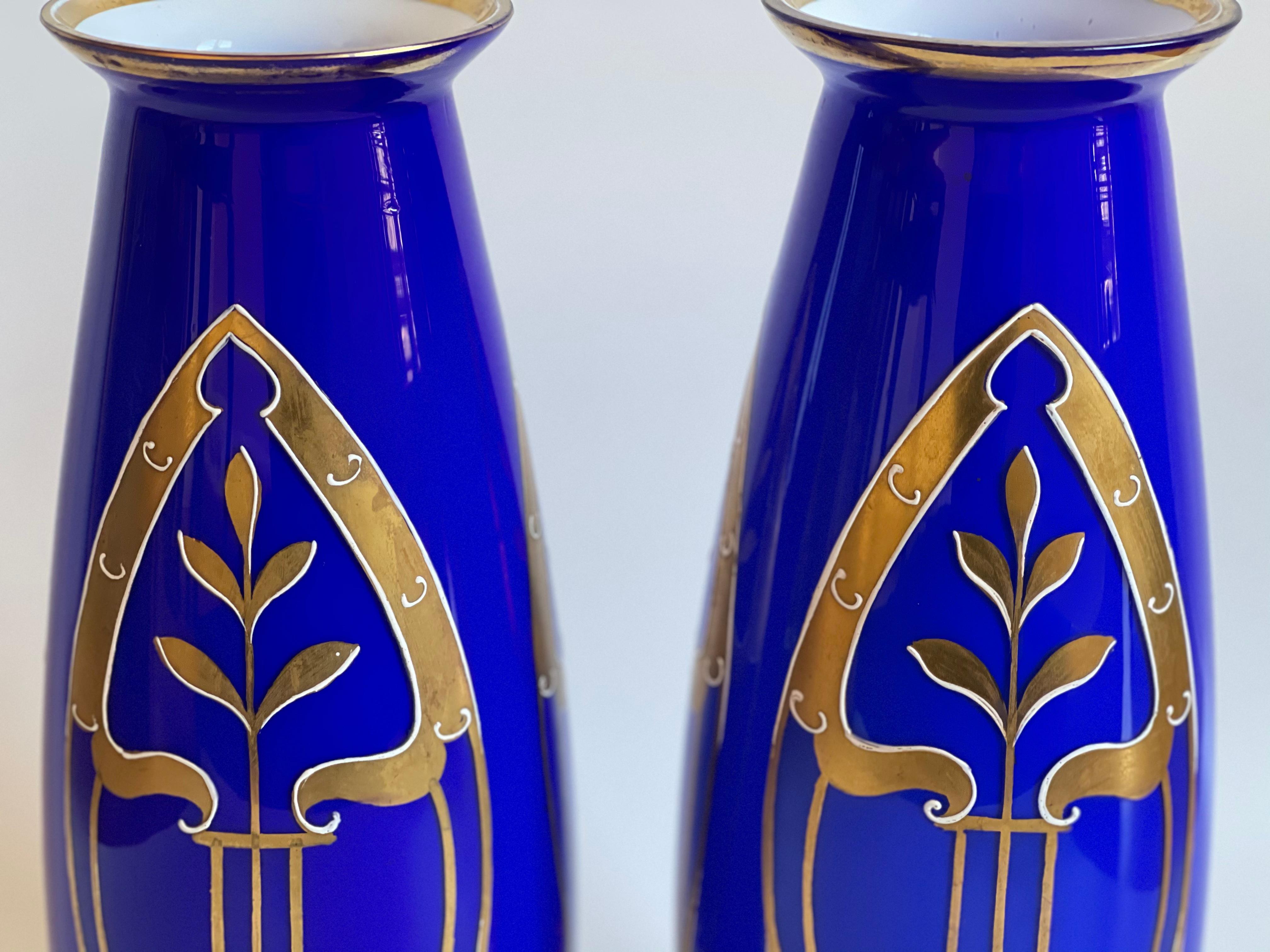 Beautiful, tall Art Deco, unmarked glass vase pair, with gold hand paintings. The two layered (blue over white) thin molded glass’ delicate walls are hand painted with thick gold relief geometric design, typical for the era. This antique item has no