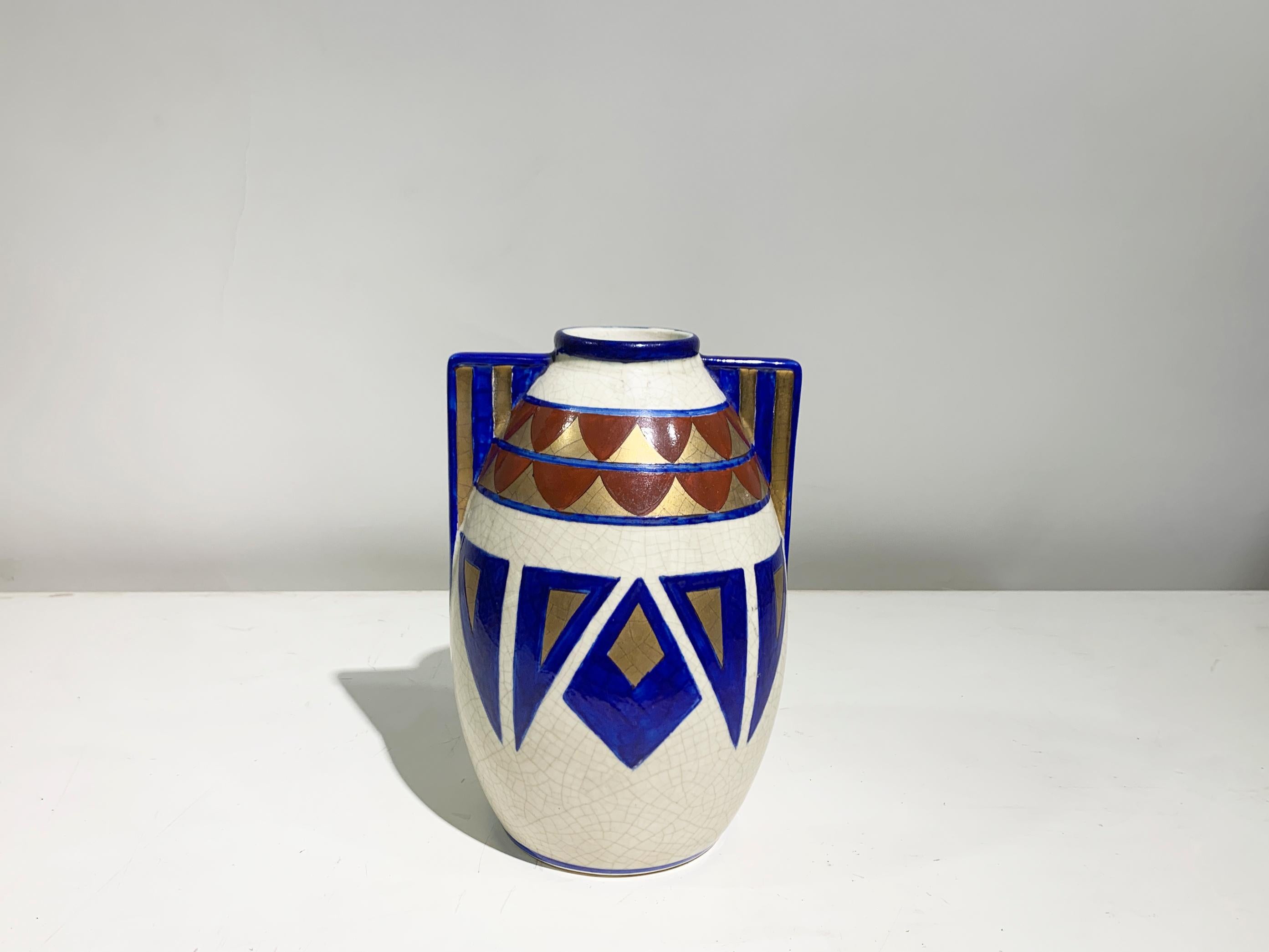 Si tratta di un sorprendente vaso in ceramica Art Déco caratterizzato da audaci motivi geometrici e da una tavolozza di colori vivaci. 

Il vaso ha una classica forma arrotondata con manici angolari e presenta una combinazione di blu cobalto
