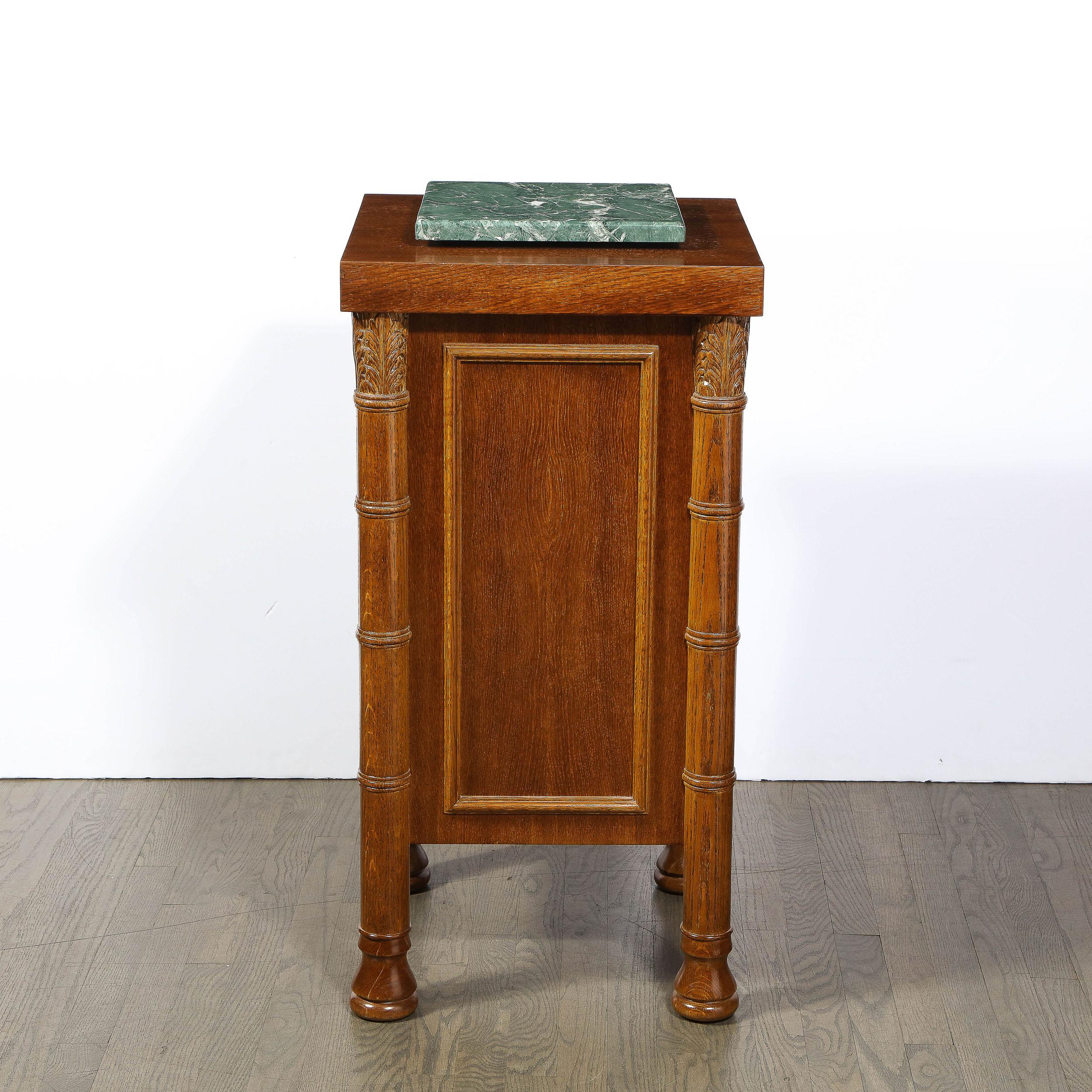 This Art Deco Pedestal originated from the United States Circa 1940 and brings along with it the design sensibility of the time. Realized in gorgeous Oak Wood with Exotic Green Marble, the body of the pedestal is detailed in rectangular beveled trim