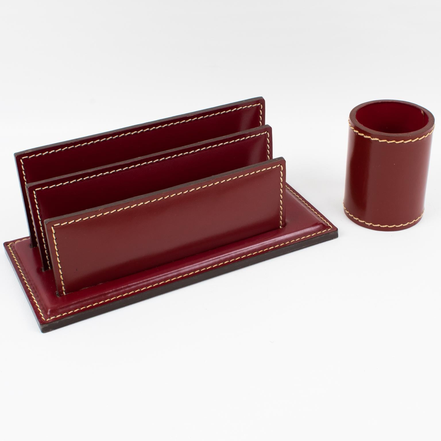 A functional 1940s modernist desk accessories set designed by ILG, Belgium, in the 1940s. The set is built with a letter holder and a pen holder. The streamlined shape boasts burgundy-red hand-stitched leather for both pieces. This gorgeous addition