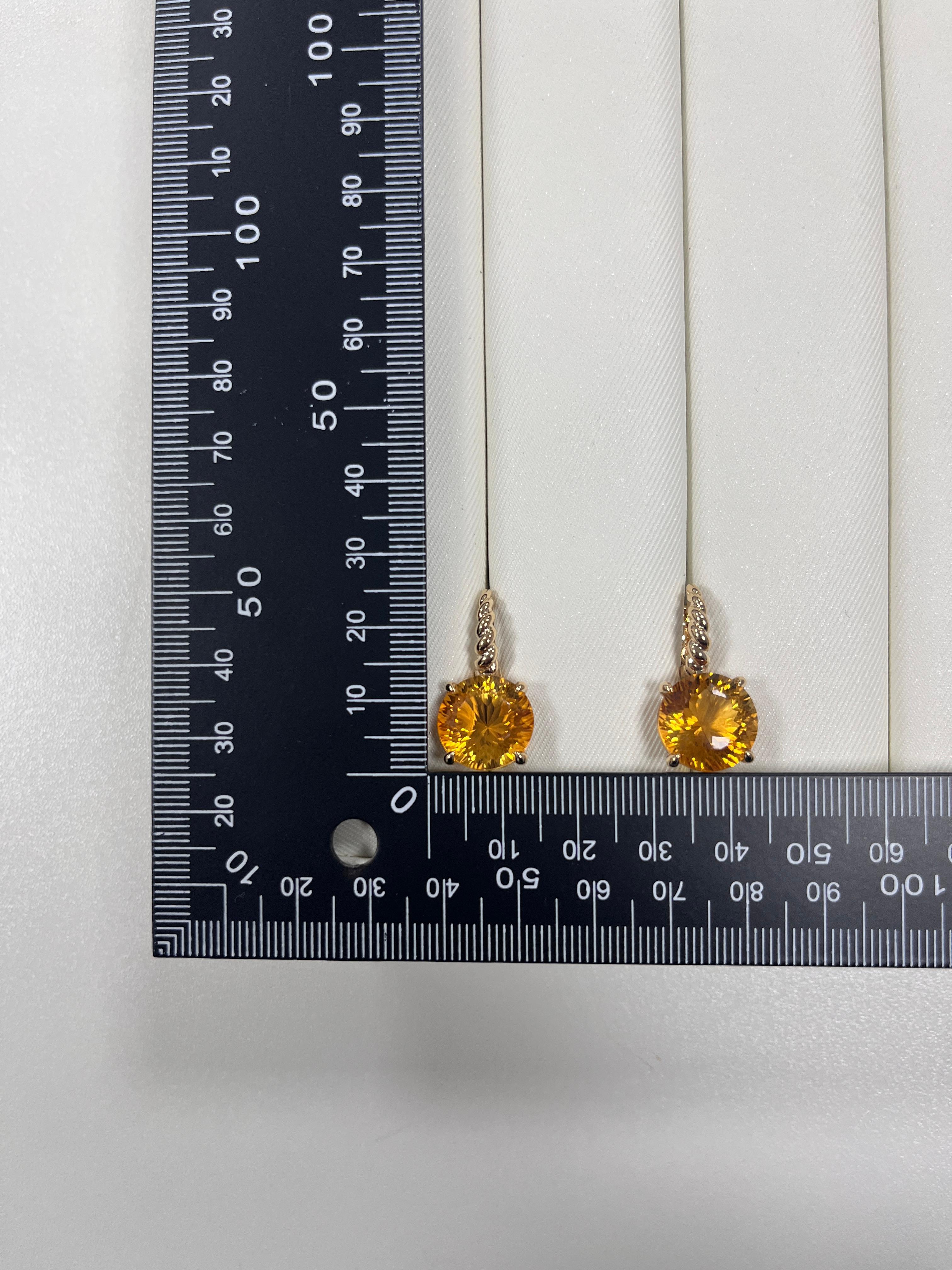 These radiant 14-karat gold earrings showcase a pair of vibrant 18.18-carat citrine gemstones, expertly cut and faceted to enhance their golden brilliance. Each citrine is securely held in a classic four-prong setting, allowing the stone's natural