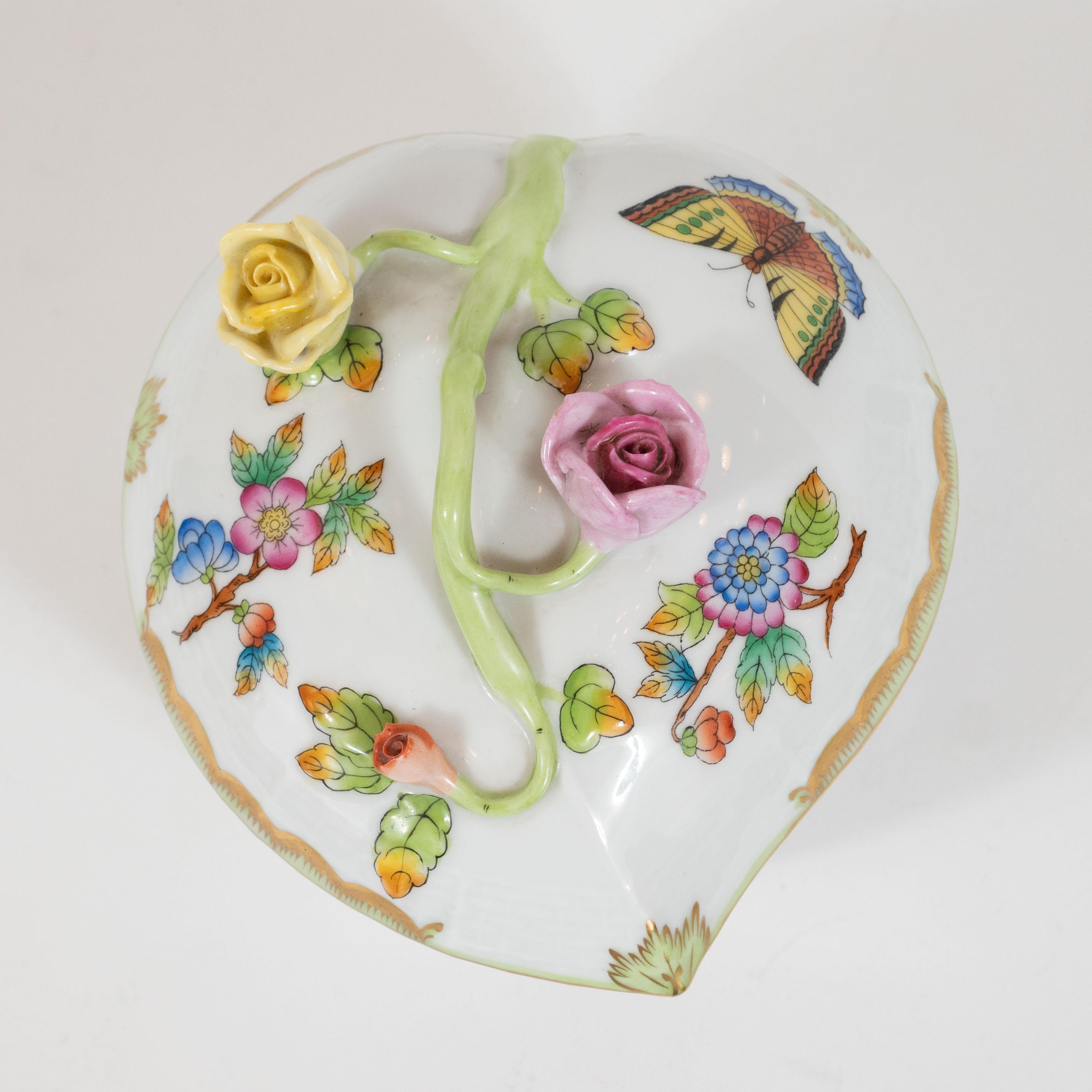 This stunning Art Deco dish was realized by the esteemed maker Herend of Hungary, circa 1930. It features sculptural handle with lemon yellow and ambrosial pink roses in relief; butterflies; as well as hand painted floral and foliate detailing