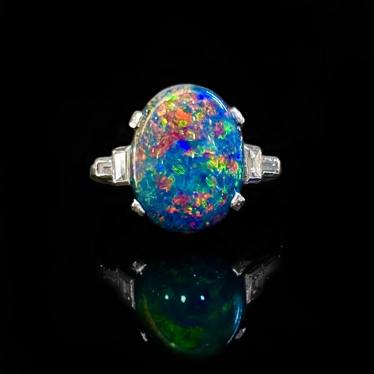Art Deco Australian Lightning Ridge Harlequin precious black opal and baguette-cut diamond engagement or cocktail ring in platinum, circa 1930, probably American. This ring features a rare natural and solid precious black opal which exuberates