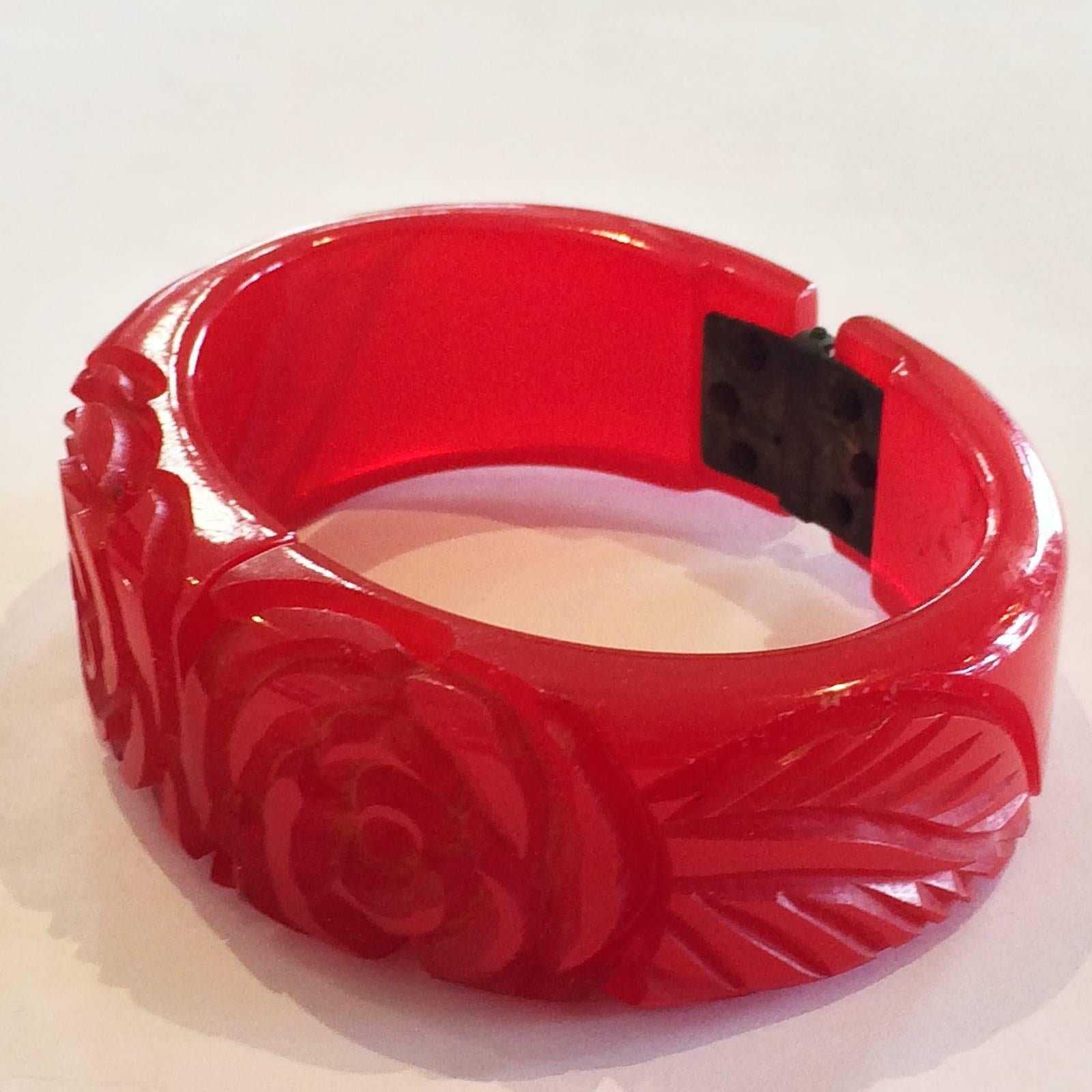 Art Deco deeply Carved Bakelite Bangle, in brilliant Ruby red, featuring Roses with a leaf at each side. All in perfect condition, no damage no losses or repairs, and the original spring hinge works perfectly. Soft, aged patina to the hinge,