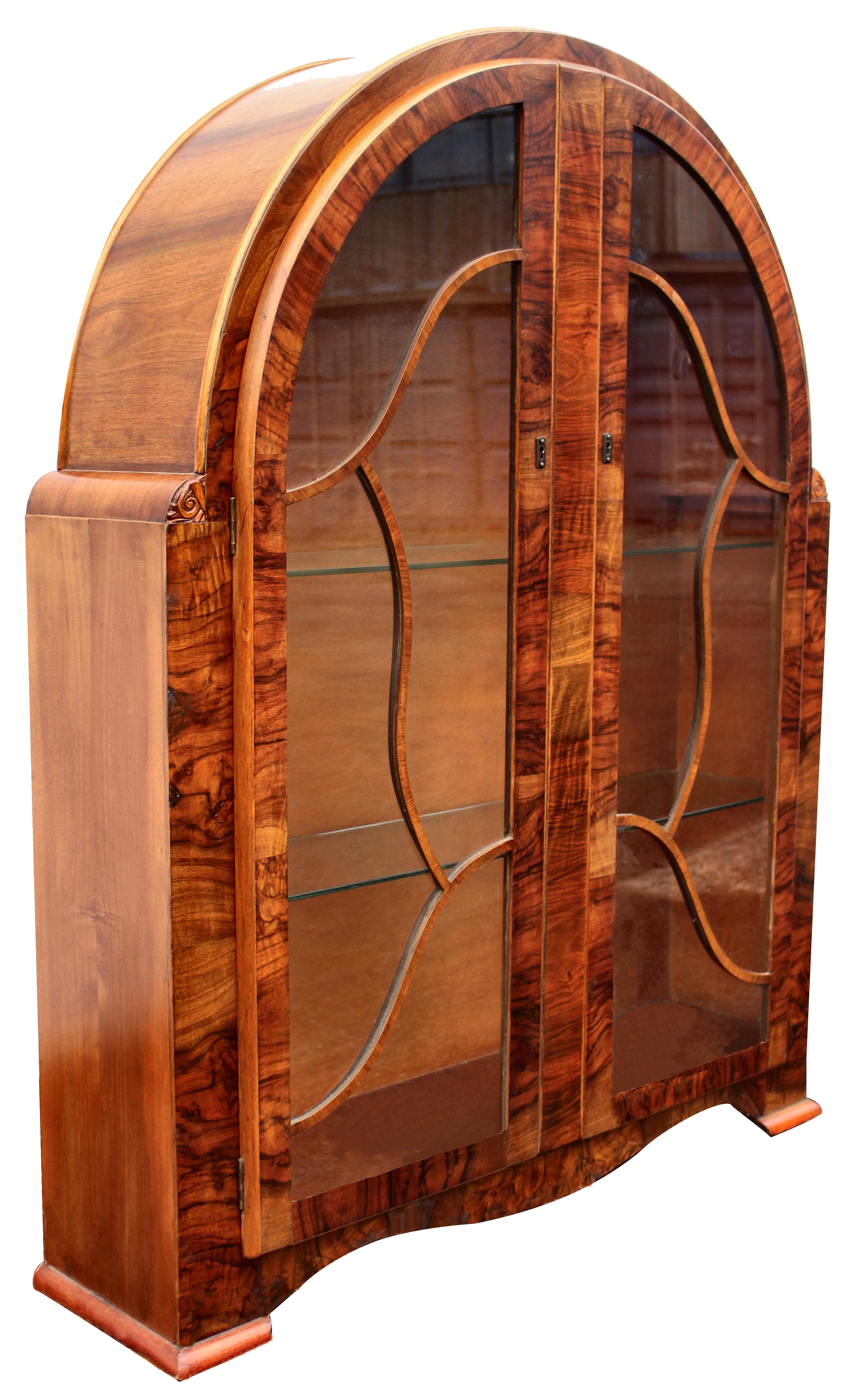 A truly beautiful 1930s Art Deco walnut cabinet of great proportions. The veneers on this cabinet are exceptional and look very impressive. The Arched top tapers down to a curvaceous base. The interior has two internal glass shelves and the very