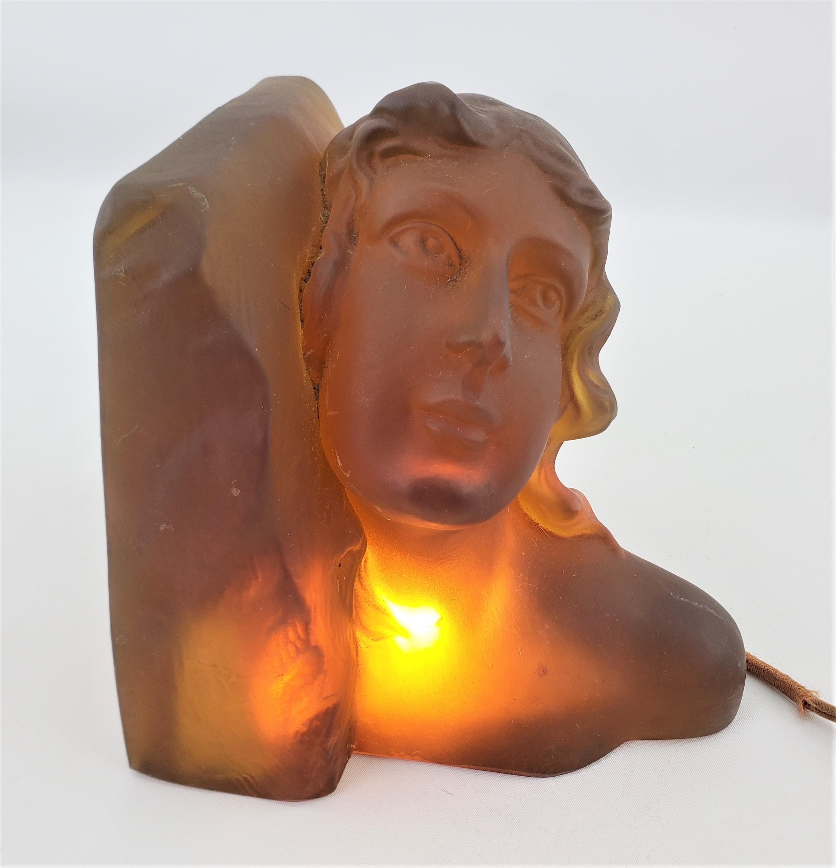 This Art Deco thick and heavy amber glass lighted table sculpture is unsigned, but presumed to have been made in the former Czech Republic in approximately 1920 in the period style. The sculpture depicts and young female, leaning against a stylized
