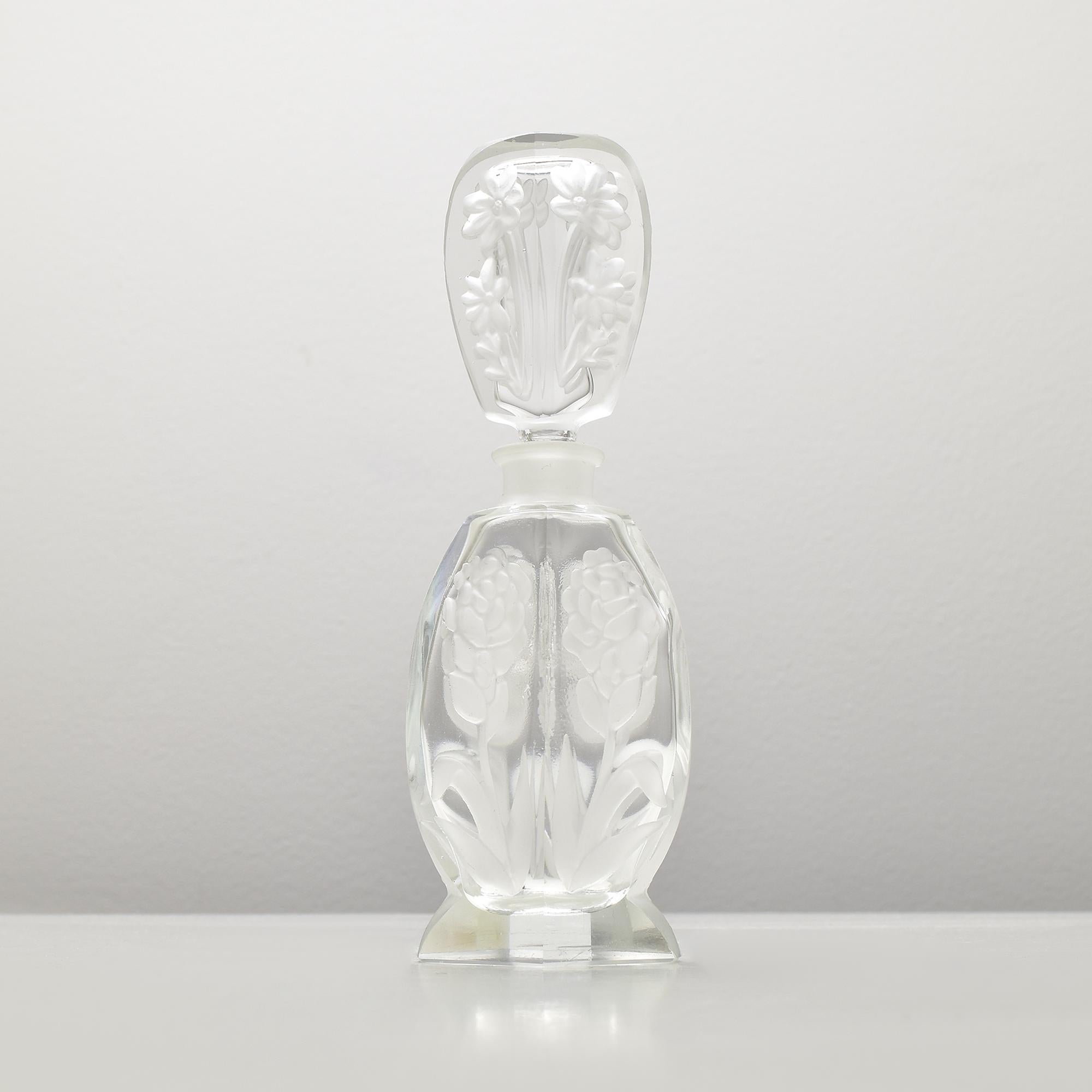 Ce superbe flacon de parfum Art déco est attribué à Heinrich Hoffmann, un maître verrier tchèque connu pour son savoir-faire exceptionnel. Doté d'élégants motifs floraux en creux, ce flacon de parfum exquis incarne la sophistication et le souci du