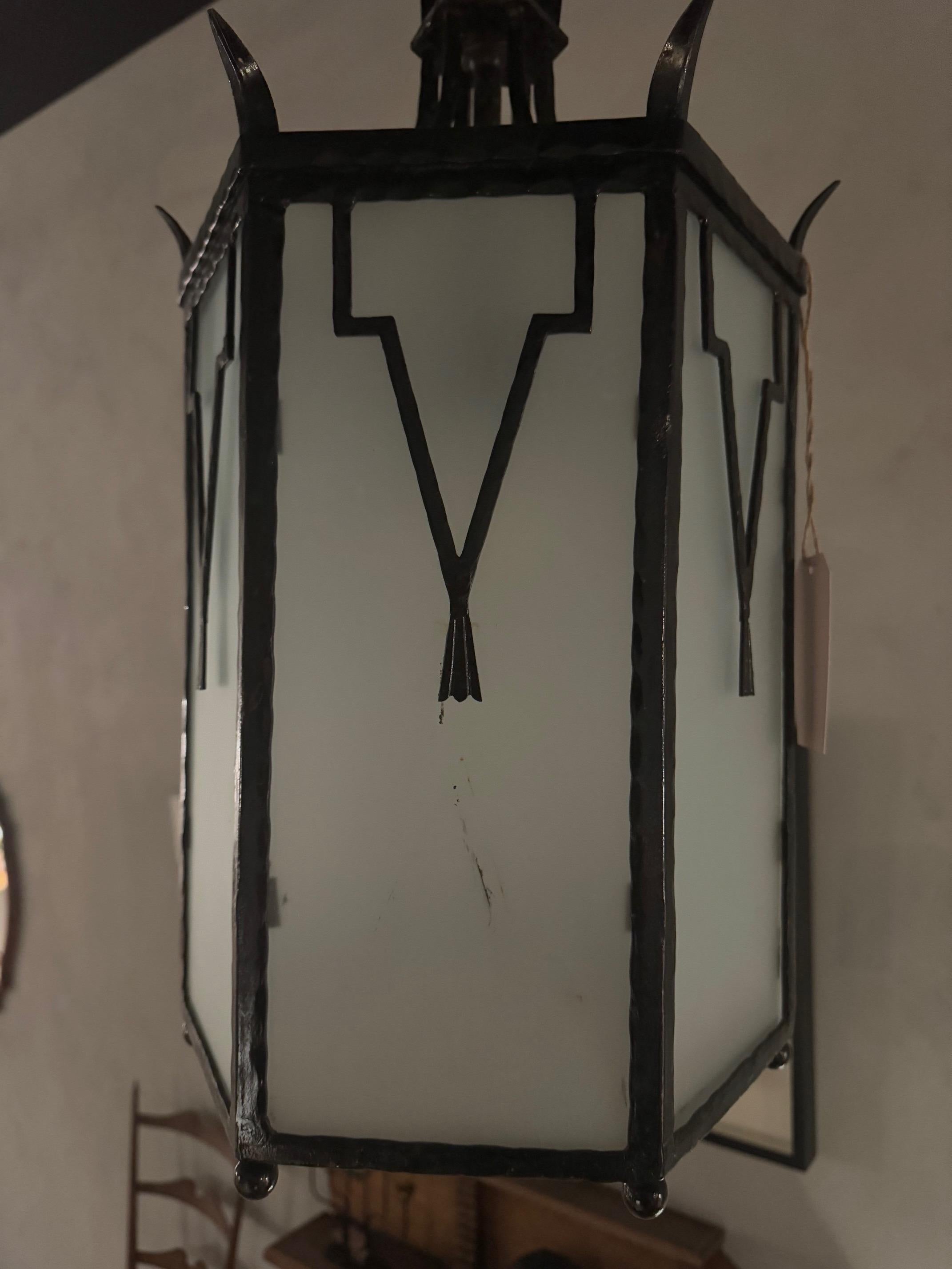 Beautiful and unique Art Deco lantern crafted from iron and glass. The symetry and geometric forms exmplifies the principles of the 1930's. The frosted glass component diffuses light softly, enhancing the ambiance. The hexagonal shape adds to the