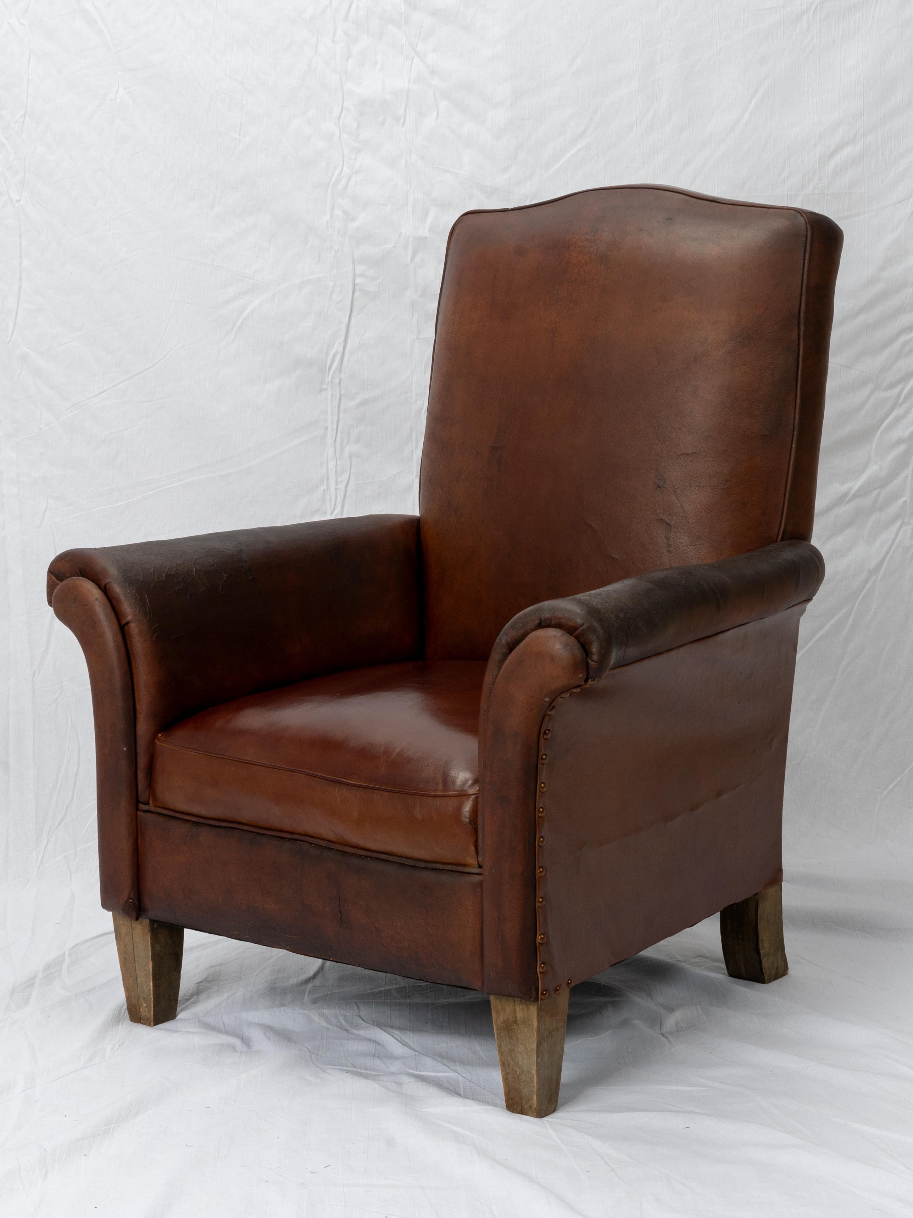 This is a classic mustache-style leather club chair from the first half of the 20th century. Likely created in the 1940s-1950s, this piece is an excellent, and somewhat unconventional, example of French craftsmanship. Sporting a wonderful deep, rich