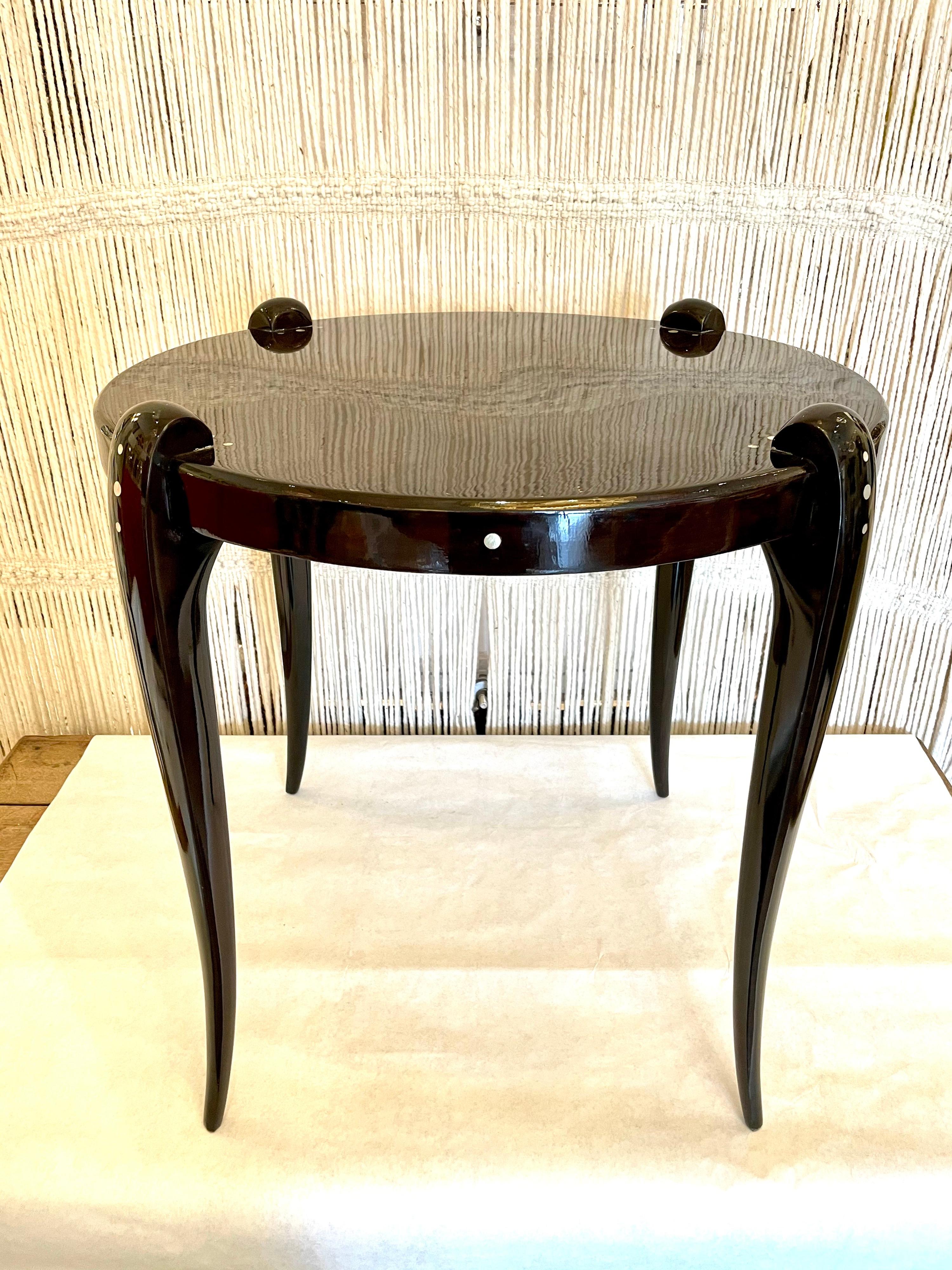 Very much in the style of the Art Deco master, Emile Ruhlmann, this cabriolet leg and round top Macassar wood table by Jallot in high lacquered finish, has mother of pearl inlay.