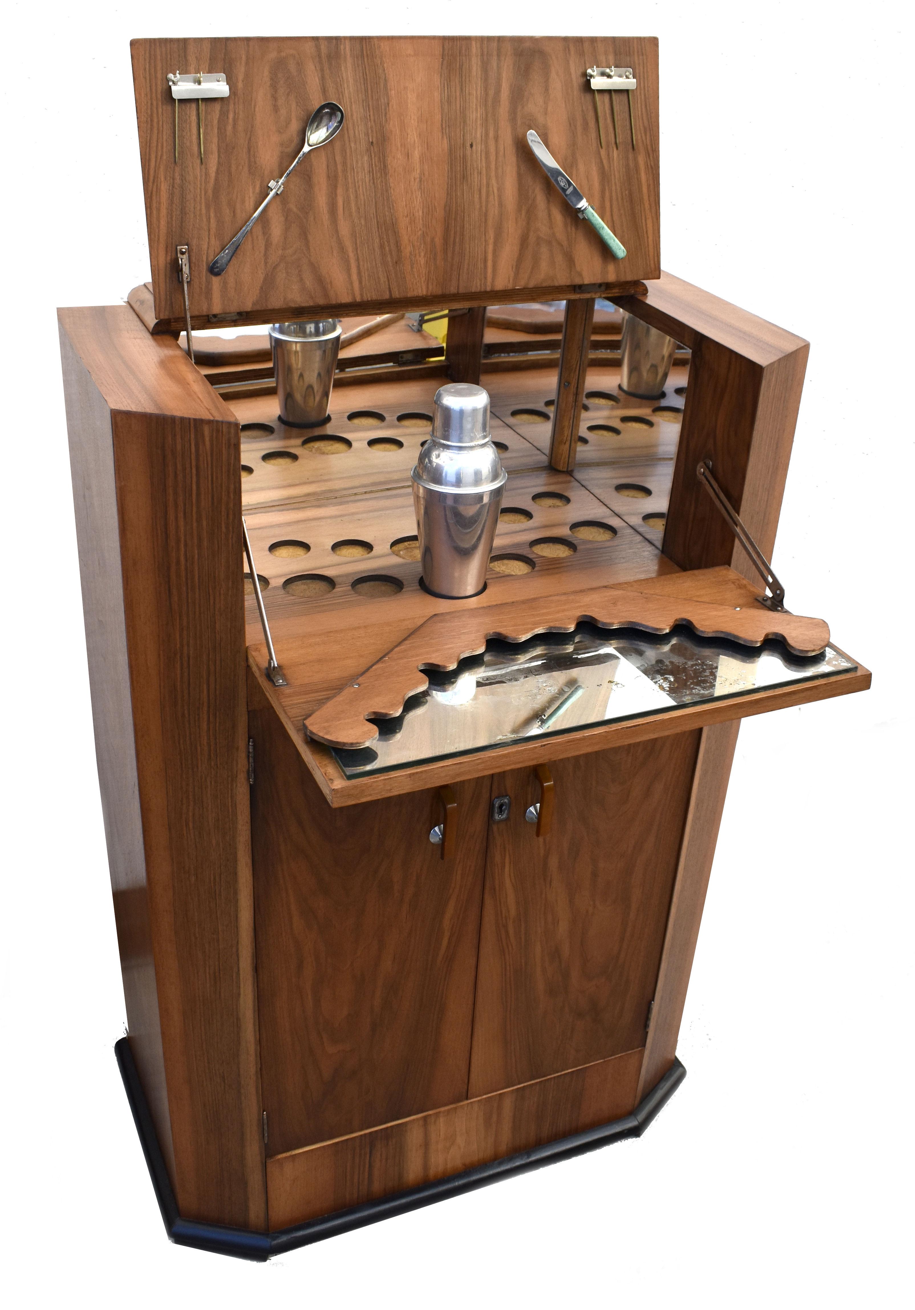 Offered for your consideration is this original 1930's Art Deco walnut upright cocktail cabinet, every Deco interior should have one of these ! Features a drop down top which reveals a mirrored interior and storage glasses. A generously sized