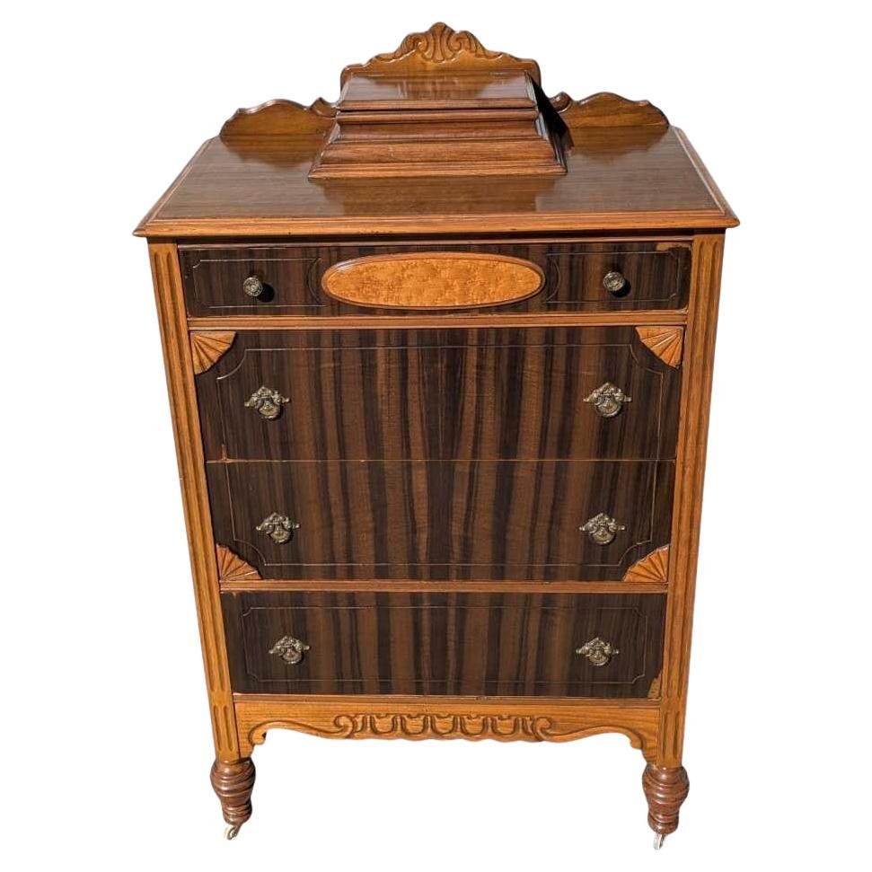 Una distintiva cómoda alta de la tradición Art Déco, fabricada en rica caoba con frentes de cajones de madera burilada y herrajes originales de latón. Esta cómoda alta presenta audaces líneas verticales y detalles curvos, que reflejan la elegancia