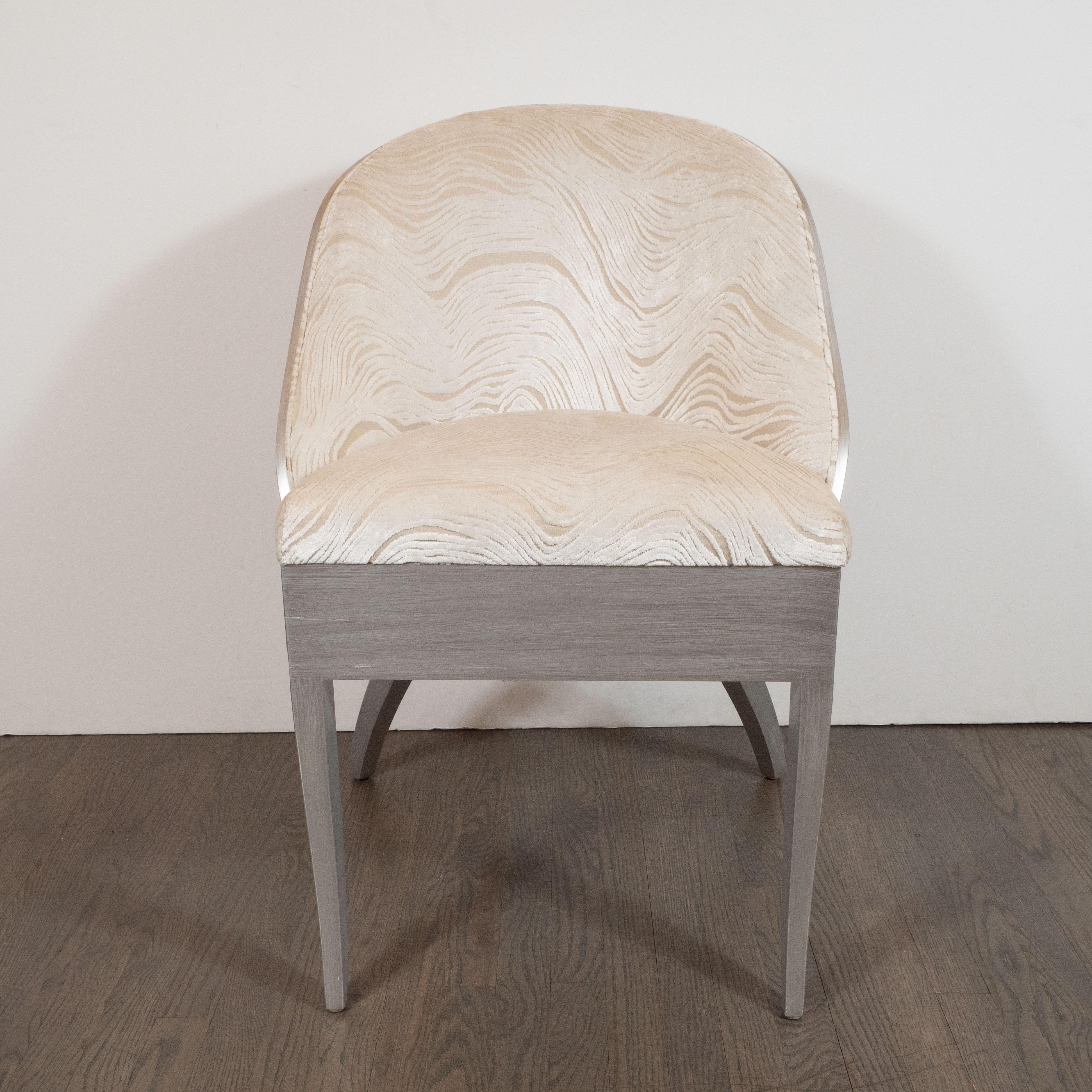 This gorgeous Art Deco Gondola desk / vanity chair features cabriolet hind legs and straight front legs finished in a radiant silver leaf. It has been newly reupholstered in a smoked oyster velvet with a geologically inspired organic gaufrage