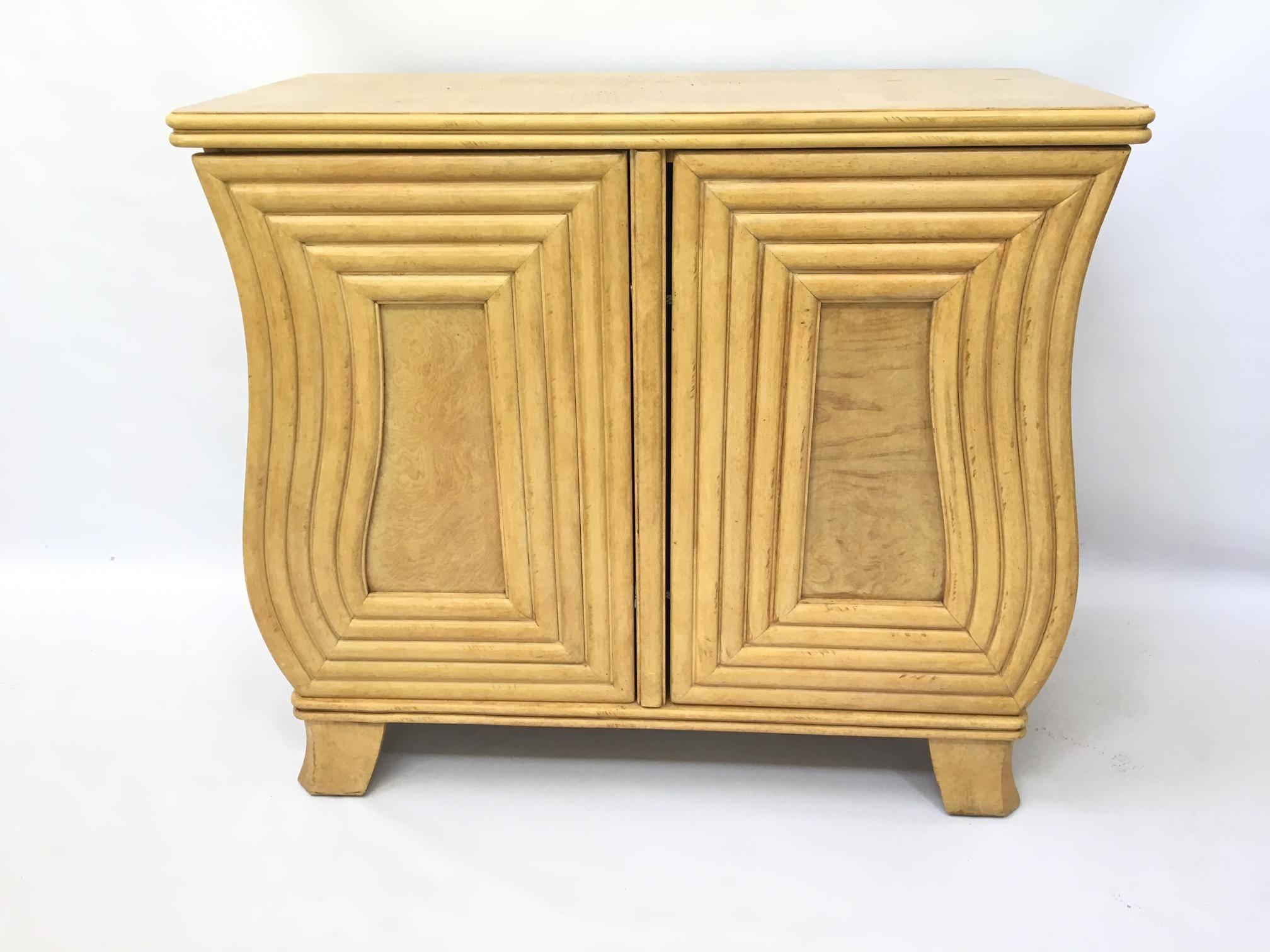 Mid-Century Modern cabinet. Features a unique curved front design with two individual doors that open opposite each other. Doors open to reveal two large storage spaces. Doors are complimented by a modern take on a split reed bamboo or rattan trim.