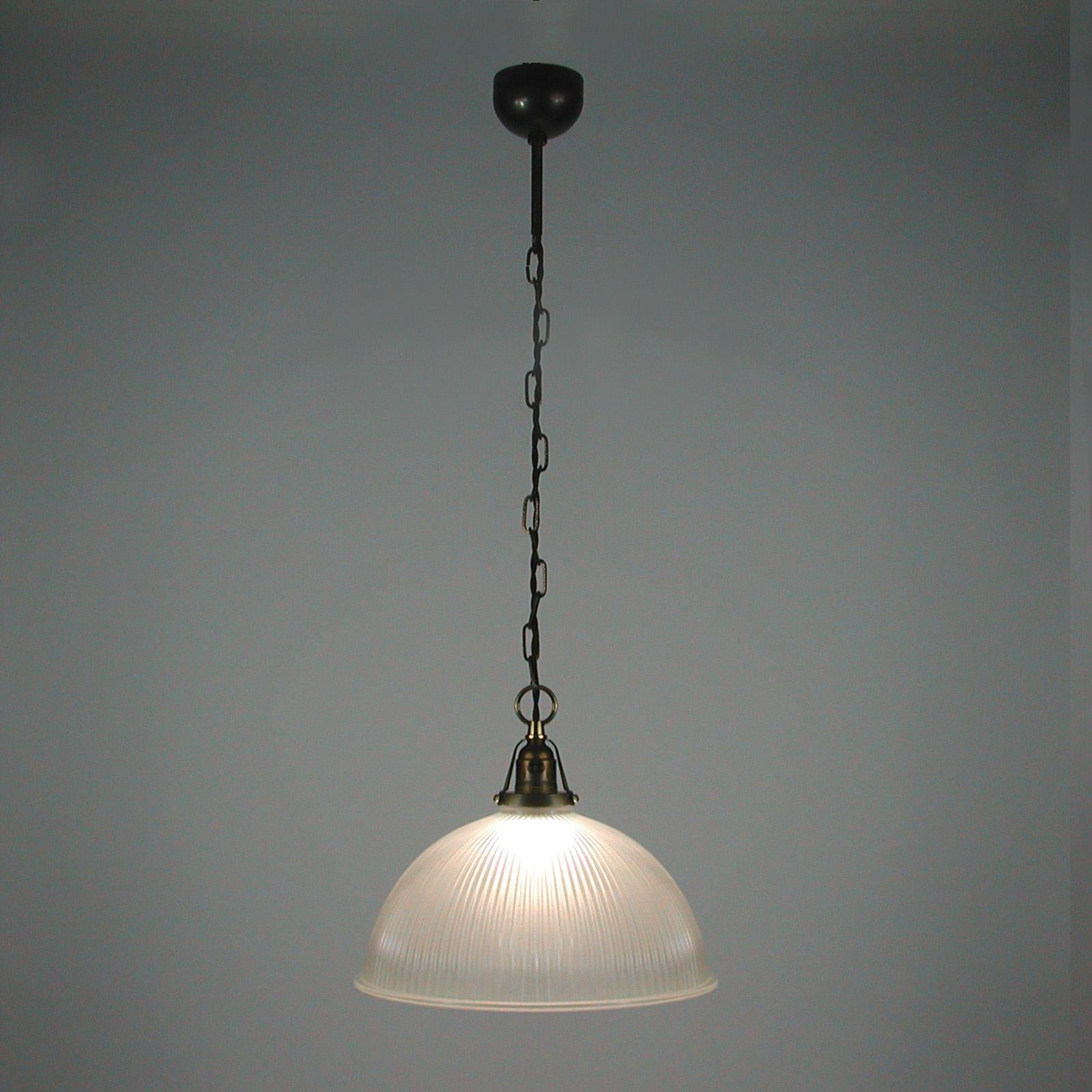 This industrial Art Deco dome shaped pendant light was manufactured in France in the 1930s. It features a clear prismatic glass Holophane lamp shade and patinated brass glass holder, chain and canopy. 

The glass gives off the best quality light.
