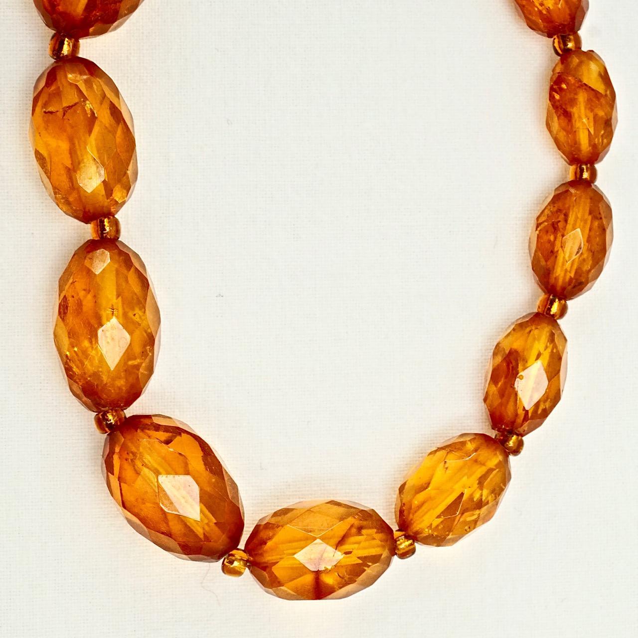 Fabulous Art Deco honey amber bead necklace with natural inclusions, and a gold plated ring bolt clasp. The beautiful faceted beads are graduated with small spacer beads in between. Measuring length 83.5cm / 32.9 inches, and the largest bead is