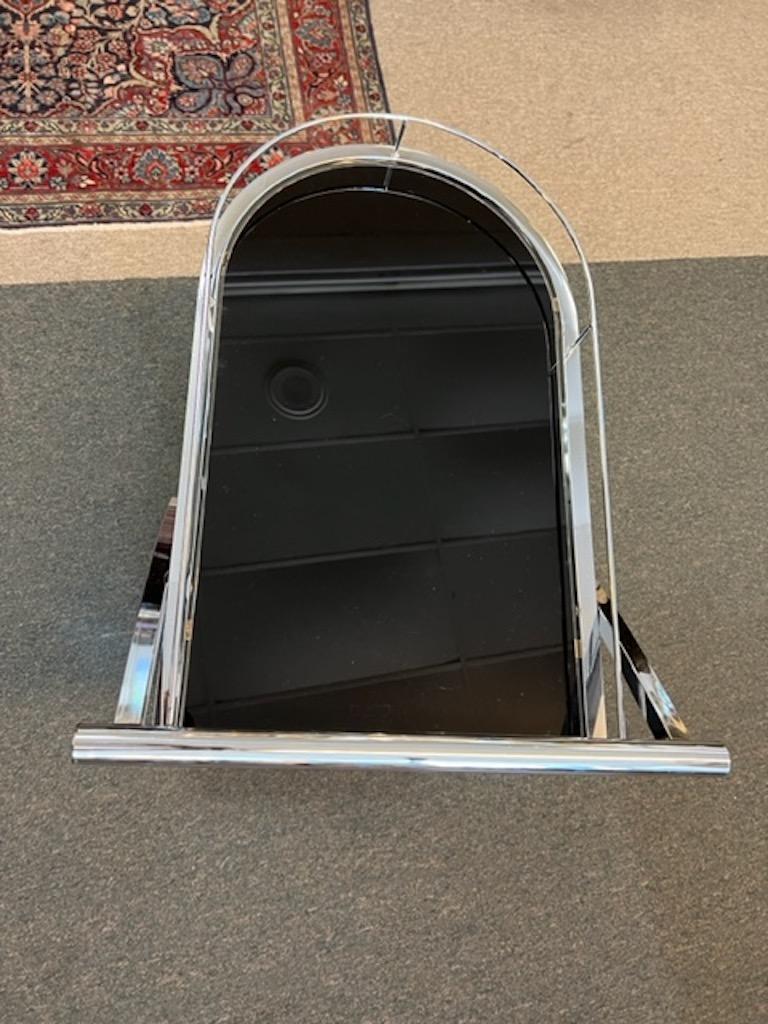 Bar cart has 2 levels, 2 shelves, made out ebonized glass. They are connected by chrome tubes. Each shelf has extended border regulator, to prevent items from falling off the shelf. Bottom has support for 3 bottles. Bar cart has chrome comfortable