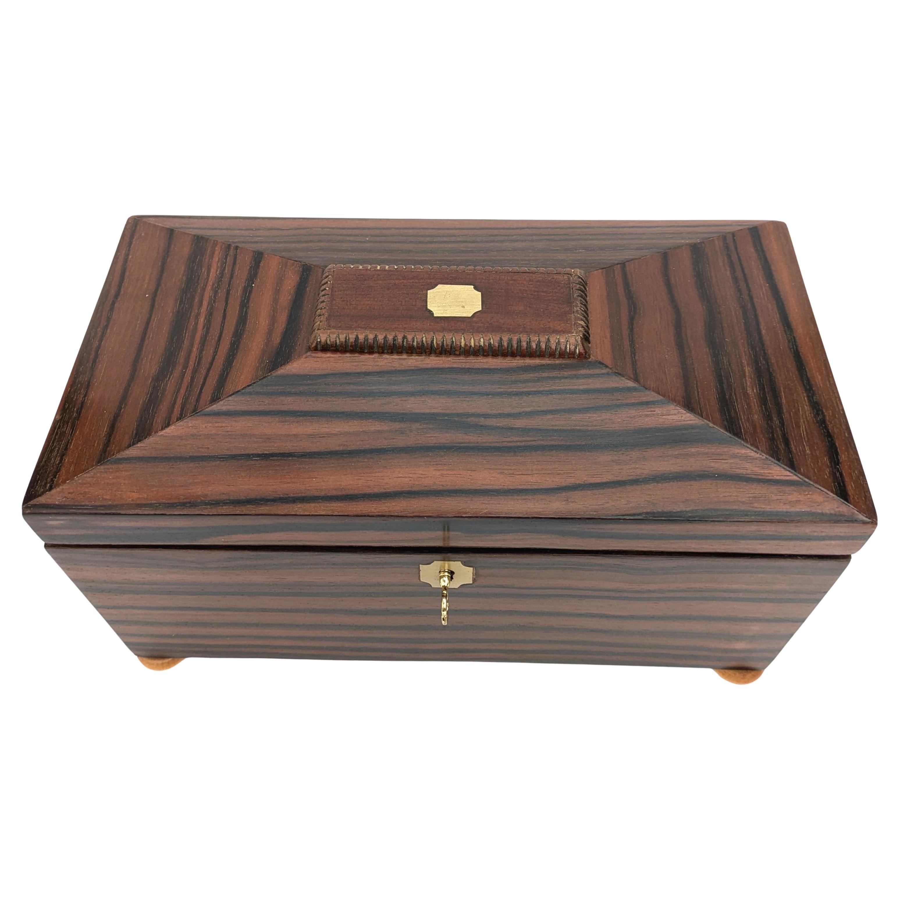 Te presentamos esta caja de madera Art Decó de aspecto magníficamente icónico, que creemos que originalmente era una caja para el té o los cigarrillos. El exterior de la caja está chapado en un hermoso ébano Macassar. El interior es una absoluta