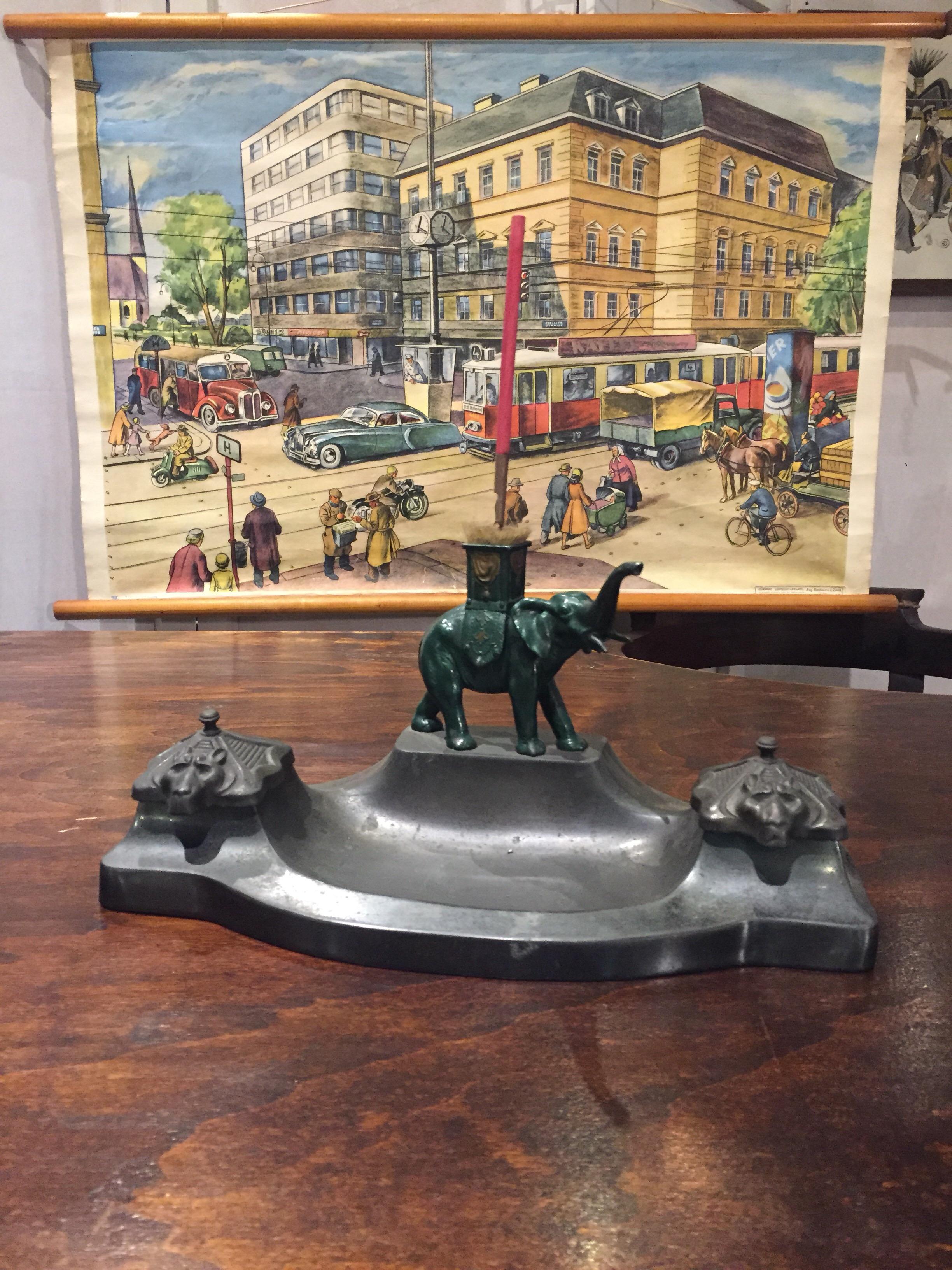 Art Deco Inkwell with  Elephant Figurine on top. 
This Inkstand with Animal has a green Metal Elephant on a metal - zamak - zamac Inkstand with 
two Glass Inkwells - Ink Containers. The lids do have a kind of Wolf on.

Desk Accesorries  - Inkset -