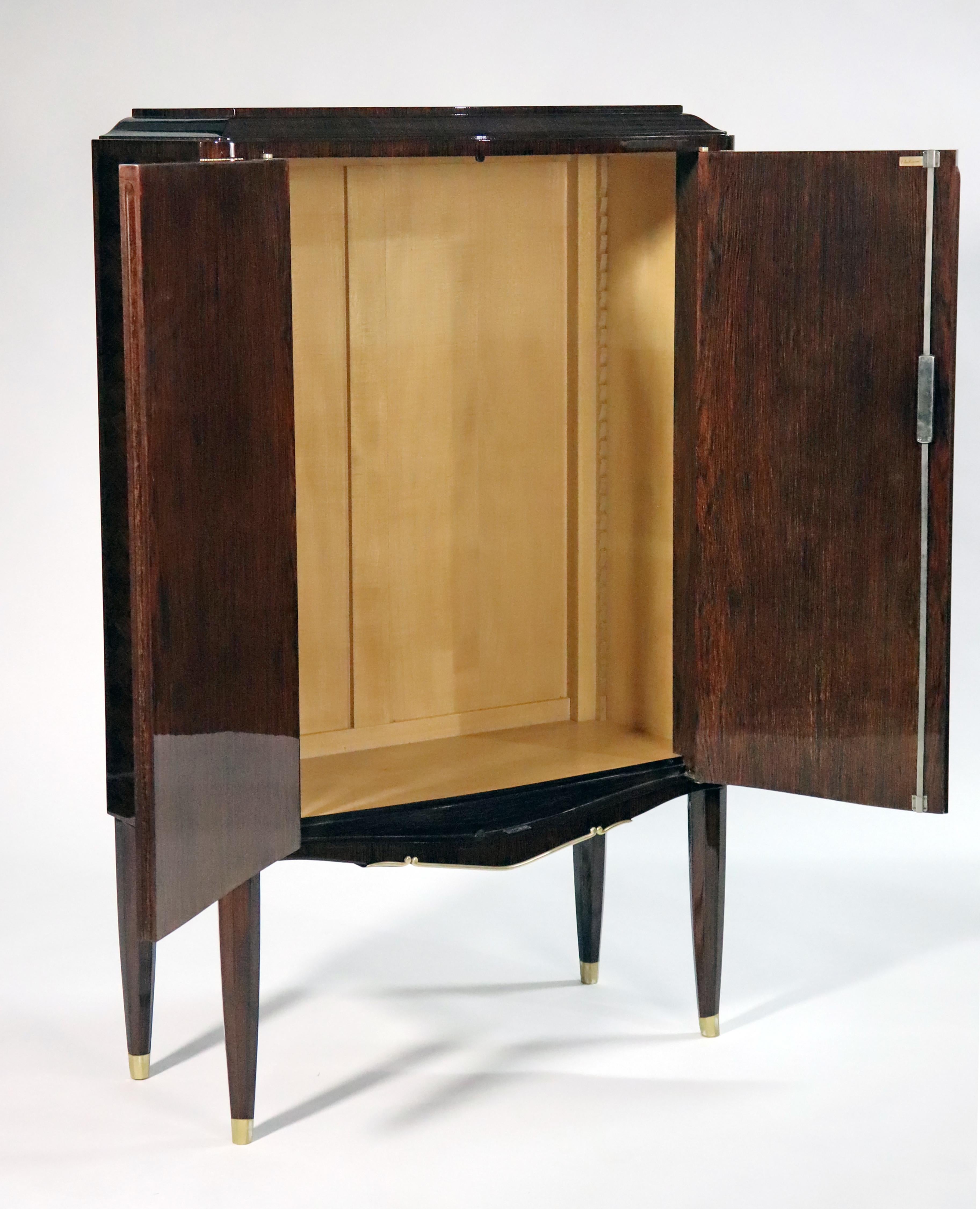 A 2-door Art Deco cabinet made from Rosewood with Bronze details along the sides.  Each door is made with a marquetry veneer and mother of pearl and ebony inlays depicting different sized wild flowers. This cabinet has 2 shelves inside in Sycamore