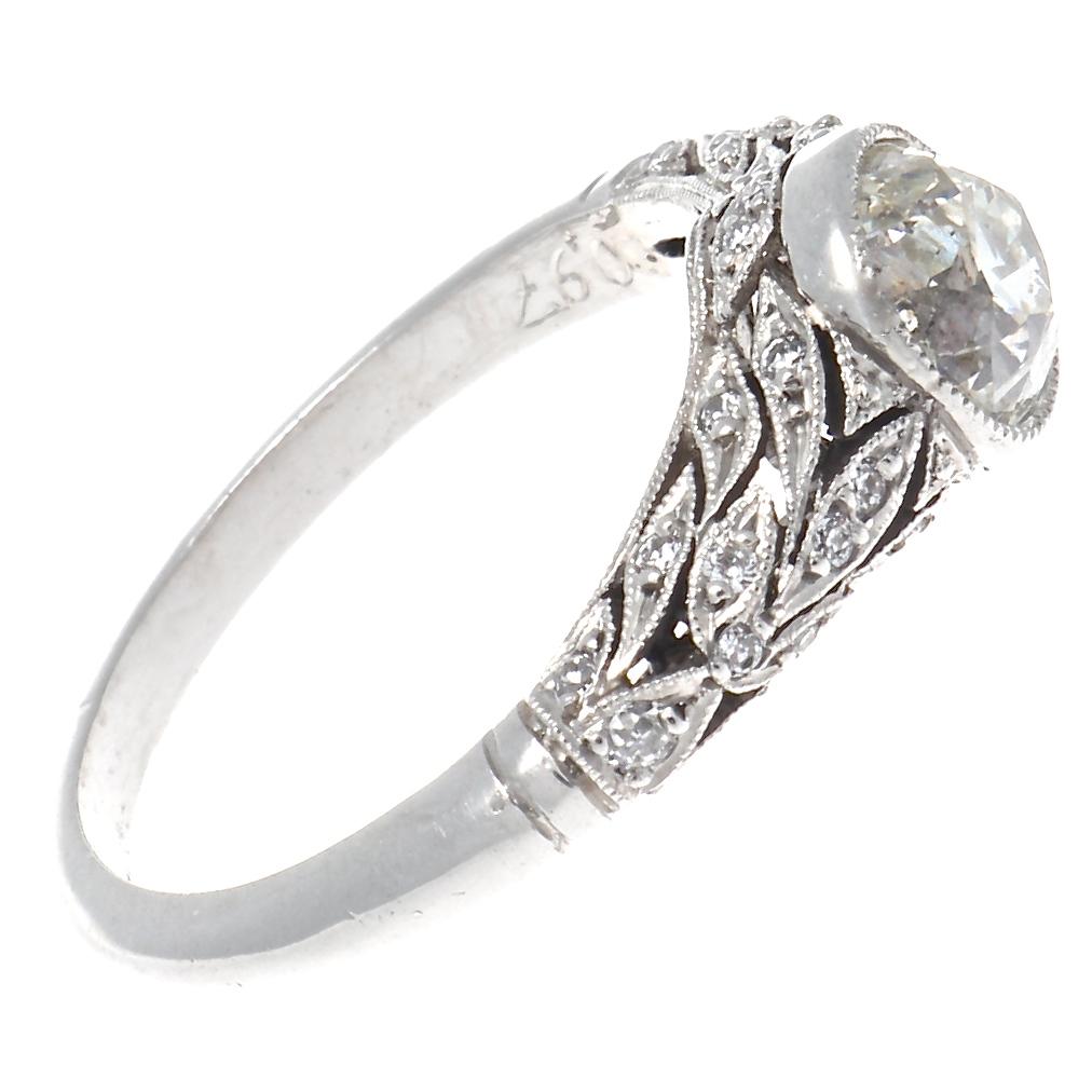 With filigree detail and mill grain edged bezel this Art Deco designed ring features a 0.97 carat old European cut diamond that creates a dazzling show within its platinum setting. Accented with 32 old European cut diamonds, the rounded shank makes