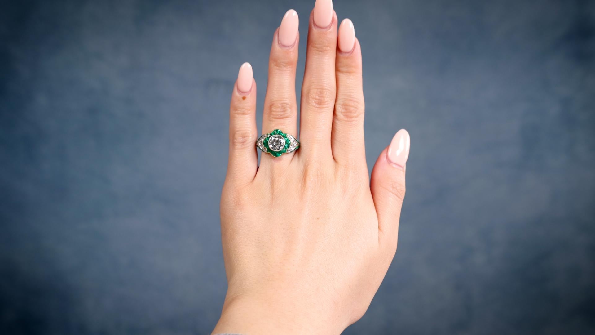 One Art Deco Inspired 1.32 Carat Transitional Cut Diamond Emerald Platinum Ring. Featuring one transitional cut diamond of 1.32 carats, graded I color VS2 clarity. Accented by 28 calibré cut emeralds with a total weight of approximately 1.40 carats,