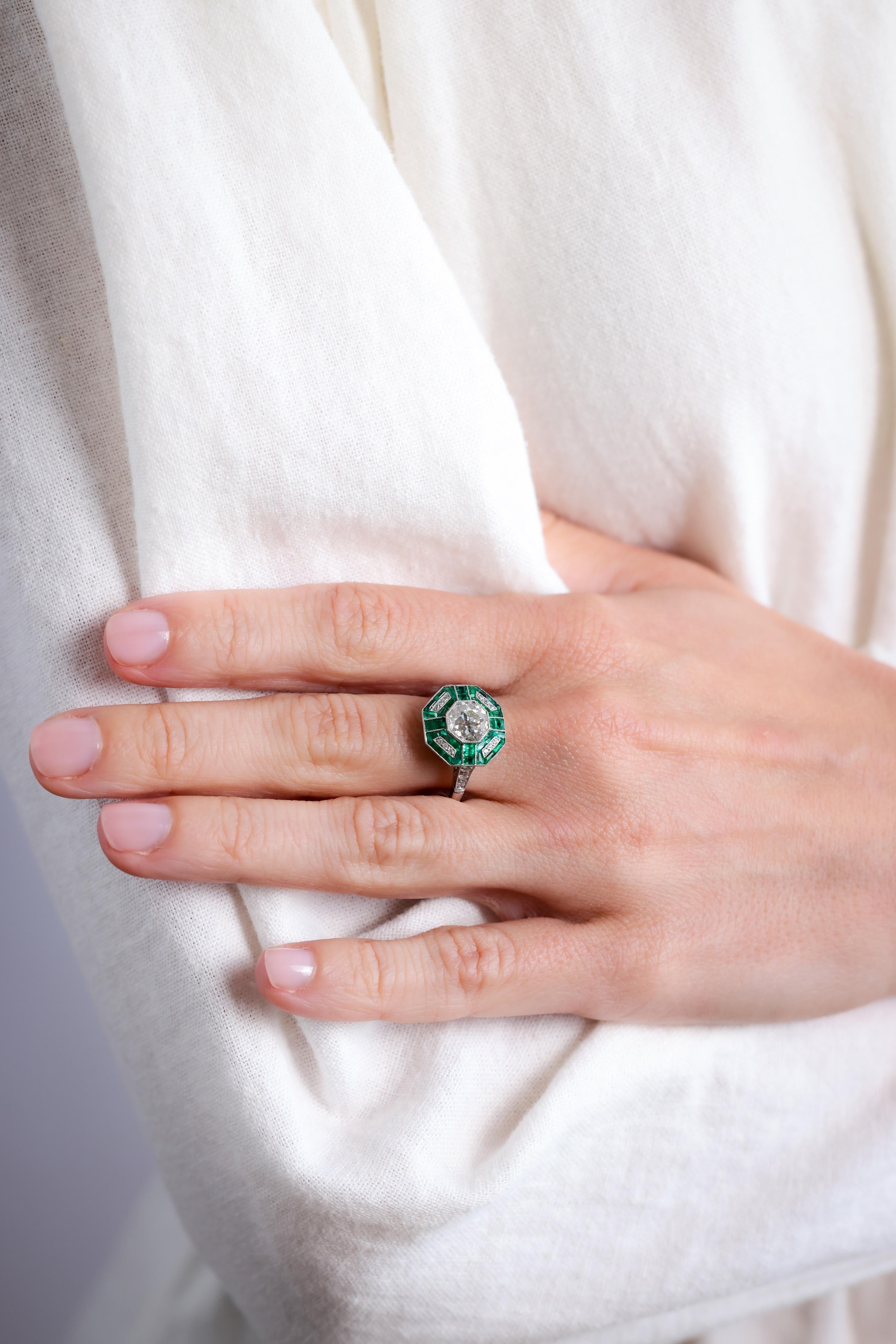Center Stone: Diamond
Cut: Old Mine
Weight: 1.45 Carat
Color: J
Clarity: SI
Accent Stone: 18 Diamonds
Cut: Old Mine 
Weight: Approximately 0.1 Carats
Color: H
Clarity: SI
Accent Stone: 32 Emeralds
Cut: Square, Trapezoid, Tapered Baguette,