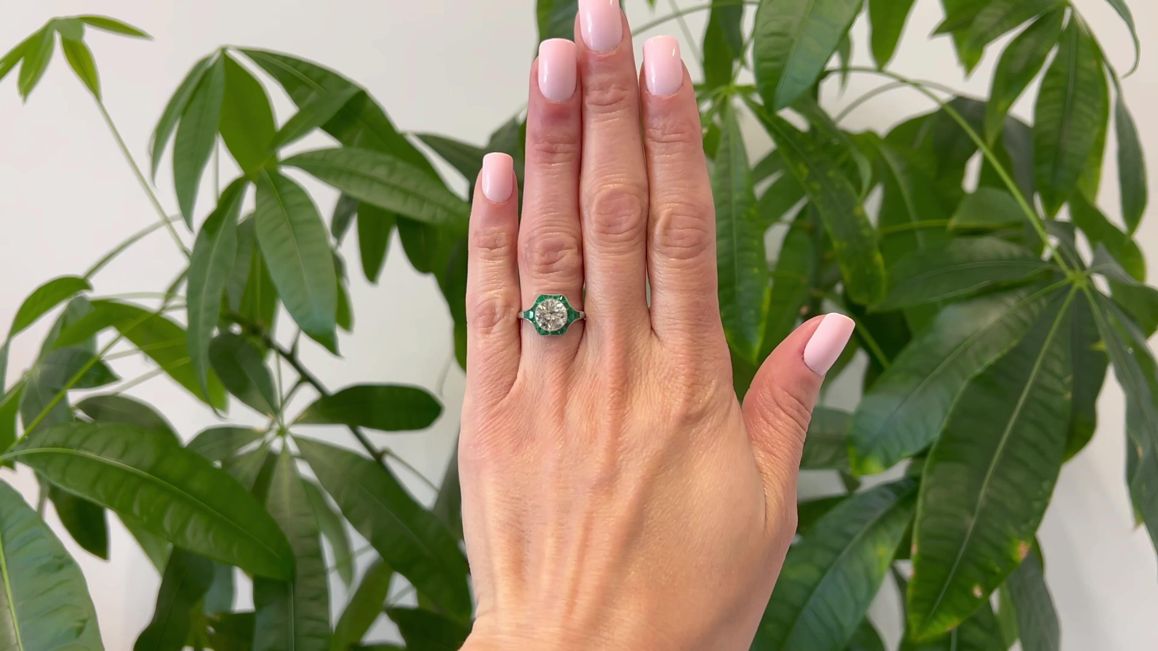 One Art Deco Inspired 2.09 Carat Round Brilliant Cut Diamond and Emerald Platinum Ring. Featuring one round brilliant cut diamond of 2.09 carats, graded M color, VS1 clarity. Accented by 16 calibré cut emeralds with a total weight of approximately