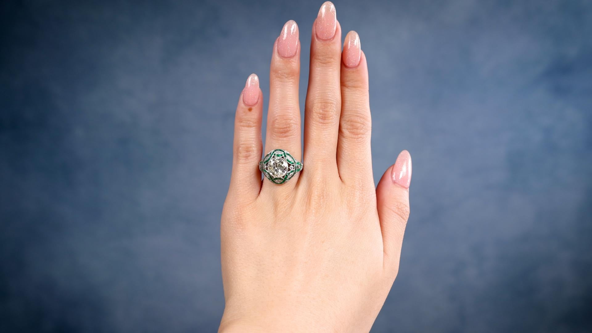 One Art Deco Inspired 2.29 Carat Transitional Cut Diamond Emerald Platinum Ring. Featuring one transitional cut diamond of 2.29 carats, graded S-T color, VS1 clarity. Accented by 56 calibré cut emeralds with a total weight of approximately 1.00
