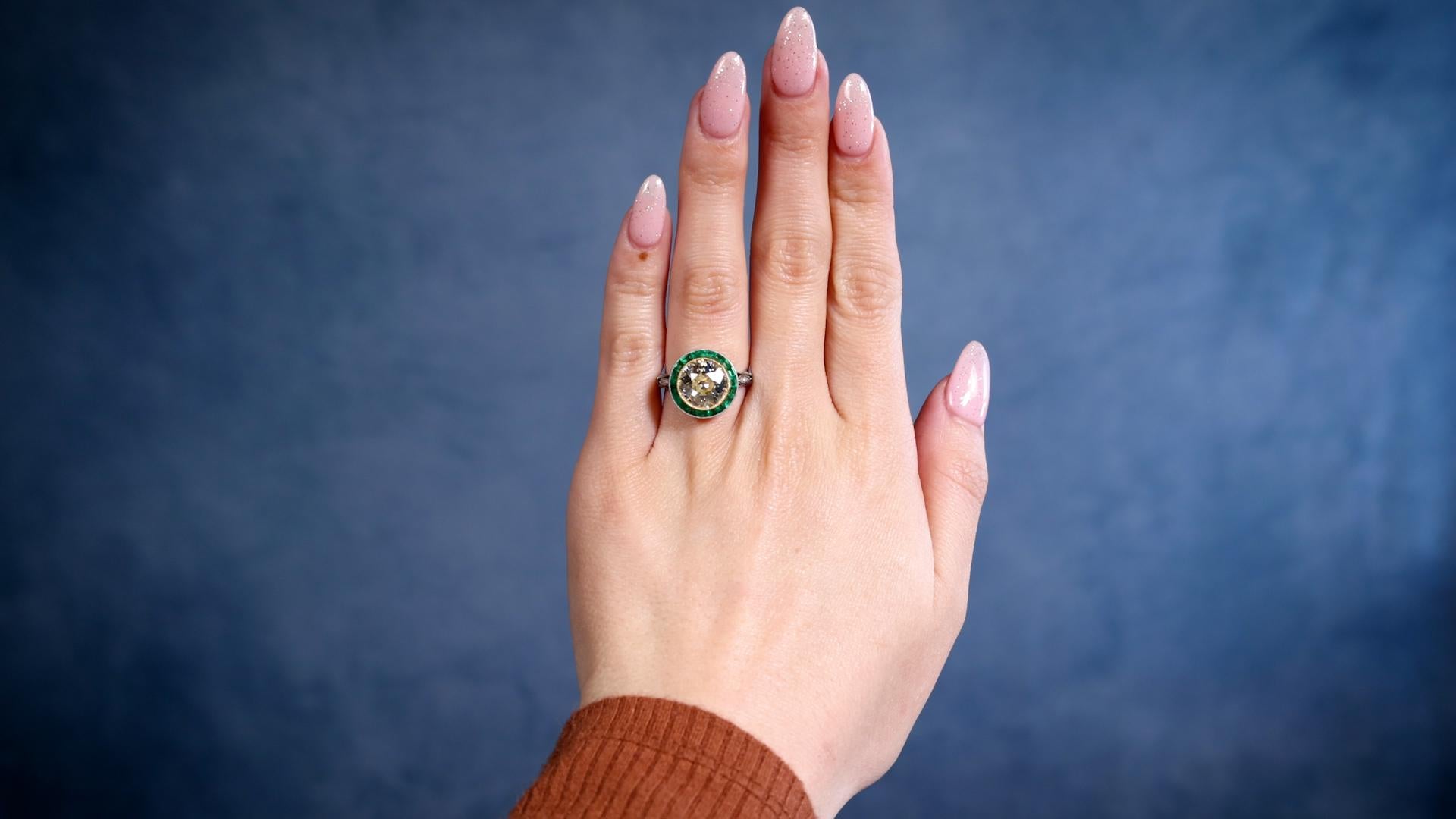 One Art Deco Inspired 3.12 Carat Old European Cut Diamond Emerald Platinum 18k Gold Target Ring. Featuring one old European cut diamond of 3.12 carats, graded O-P color, SI1 clarity. Accented by 18 calibre cut emeralds with a total weight of