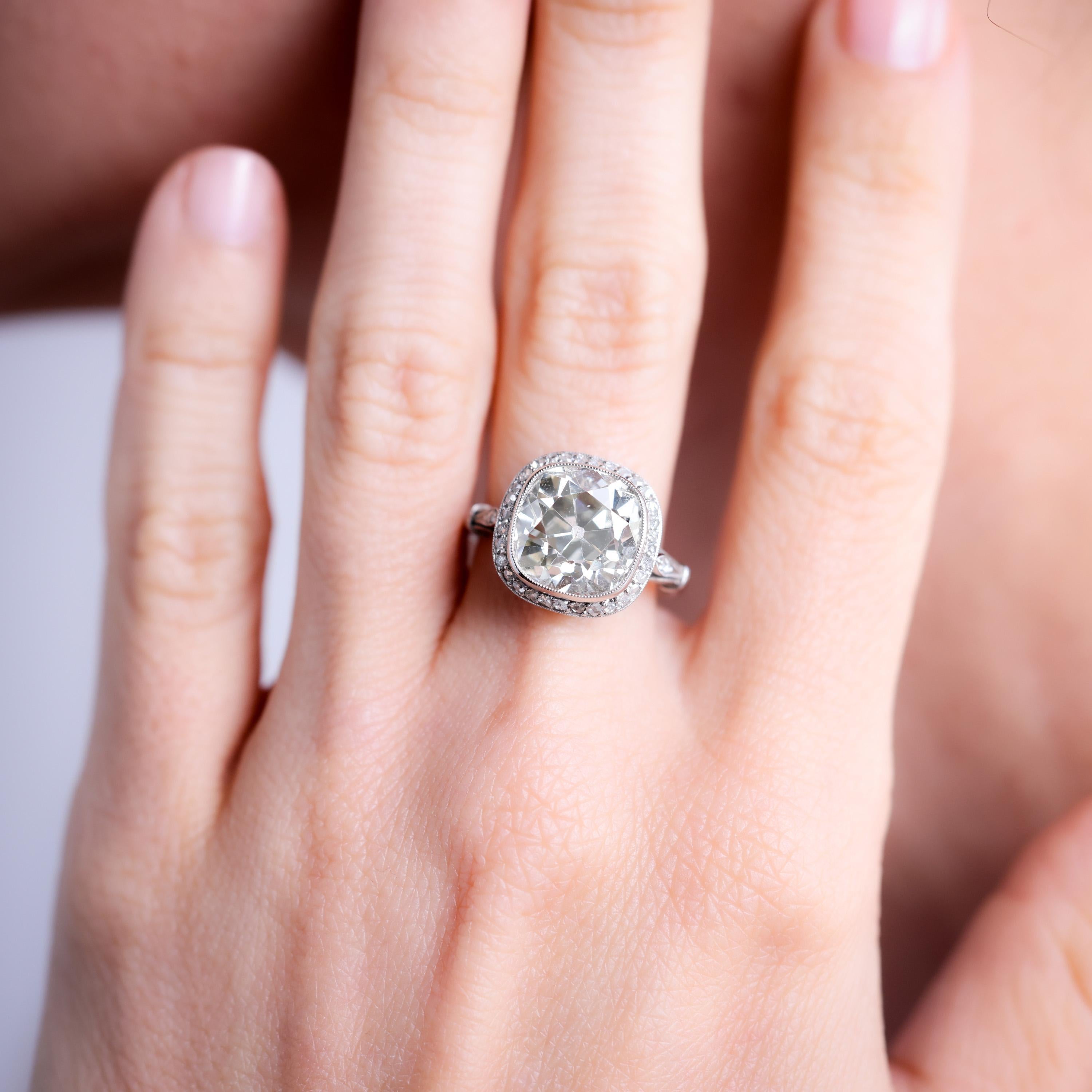 Center Stone: Diamond
Cut: Old Mine
Weight: 6 Carat
Color: M
Clarity: SI
Accent Stone: 36 Diamonds
Cut: Rose 
Weight: Approximately 0.3 Carats
Color: H
Clarity: SI
Metal: Platinum
Era: Modern in the Style of Art Deco
Circa: 2020's
Hallmarks: Stone