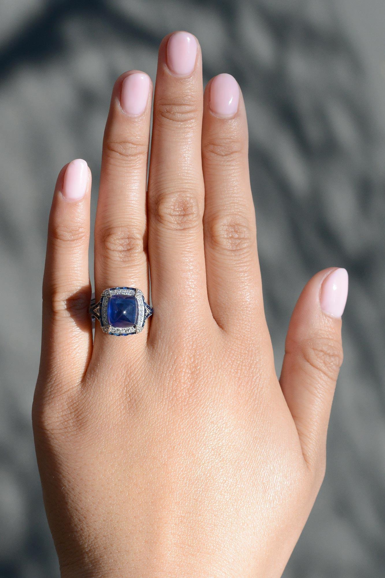 A jaw-dropping sugar loaf sapphire is the star of the show in this Art Deco style ring. This unique cut produces a vivacious, velvety blue color that pops and is named for the famed Brazilian mountain. The double halo of diamonds and buff top