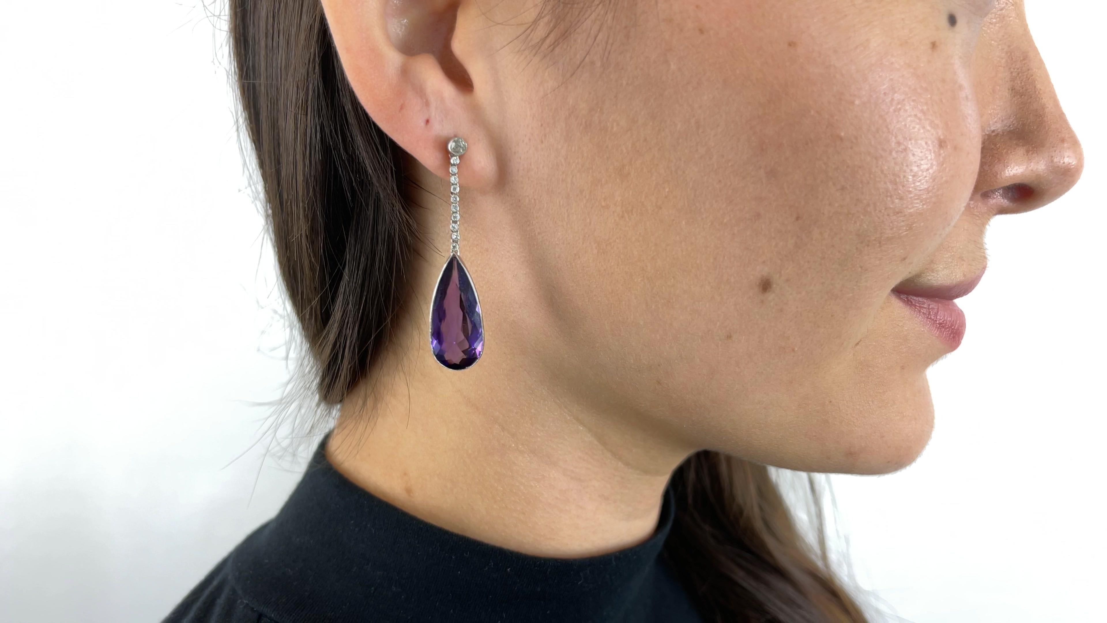 One Pair of Art Deco Inspired Amethyst Diamond Drop Earrings. Featuring two pear shaped amethysts weighing approximately 6.80 carat and 6.40 carat. Accented by 22 old European cut diamonds with a total weight of approximately 0.40 carats, graded H