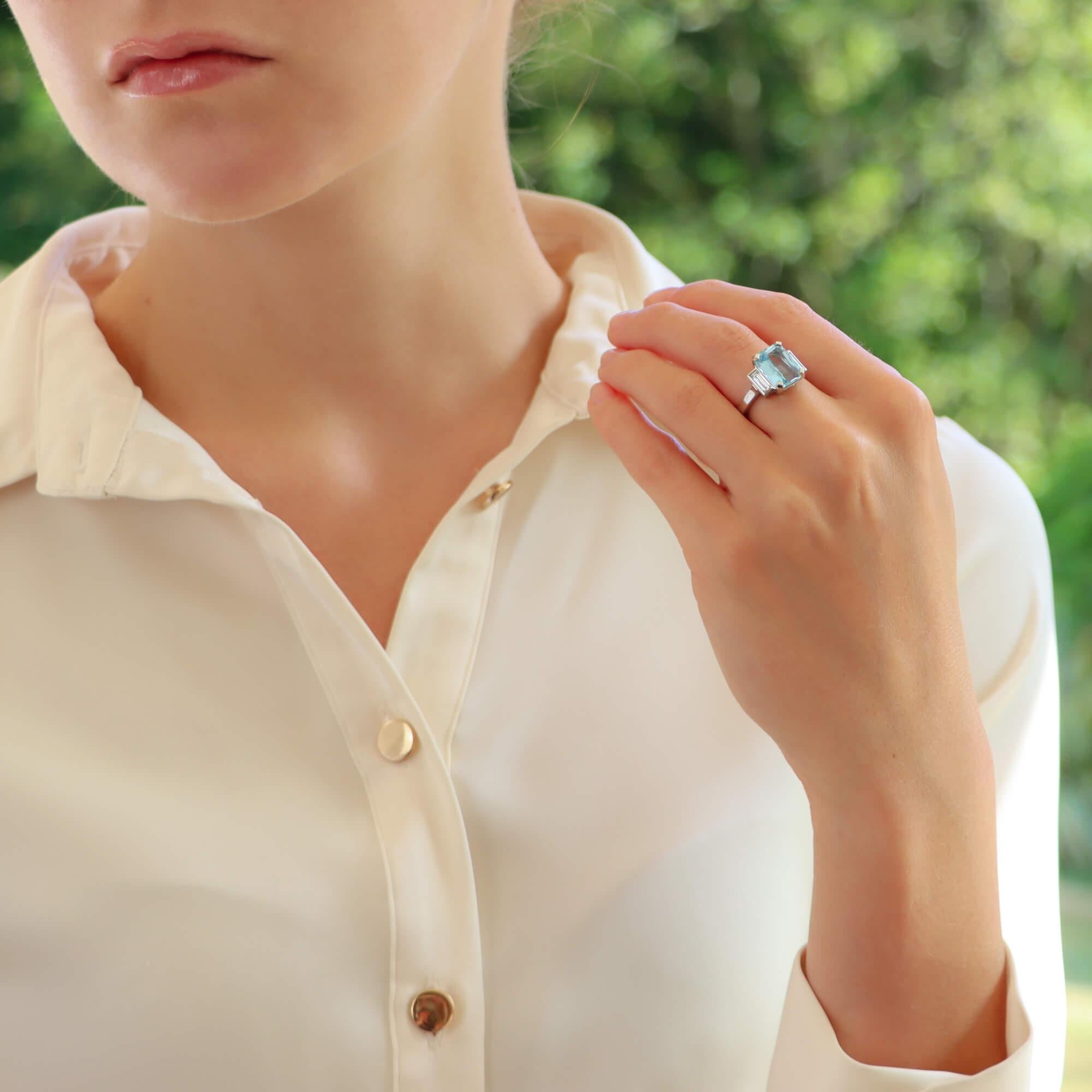 A beautiful Art Deco inspired aquamarine and diamond cocktail ring set in platinum.

This piece is predominantly set with a sky-blue coloured emerald mixed cut aquamarine which is four claw set to centre. To each side of the aquamarine are single