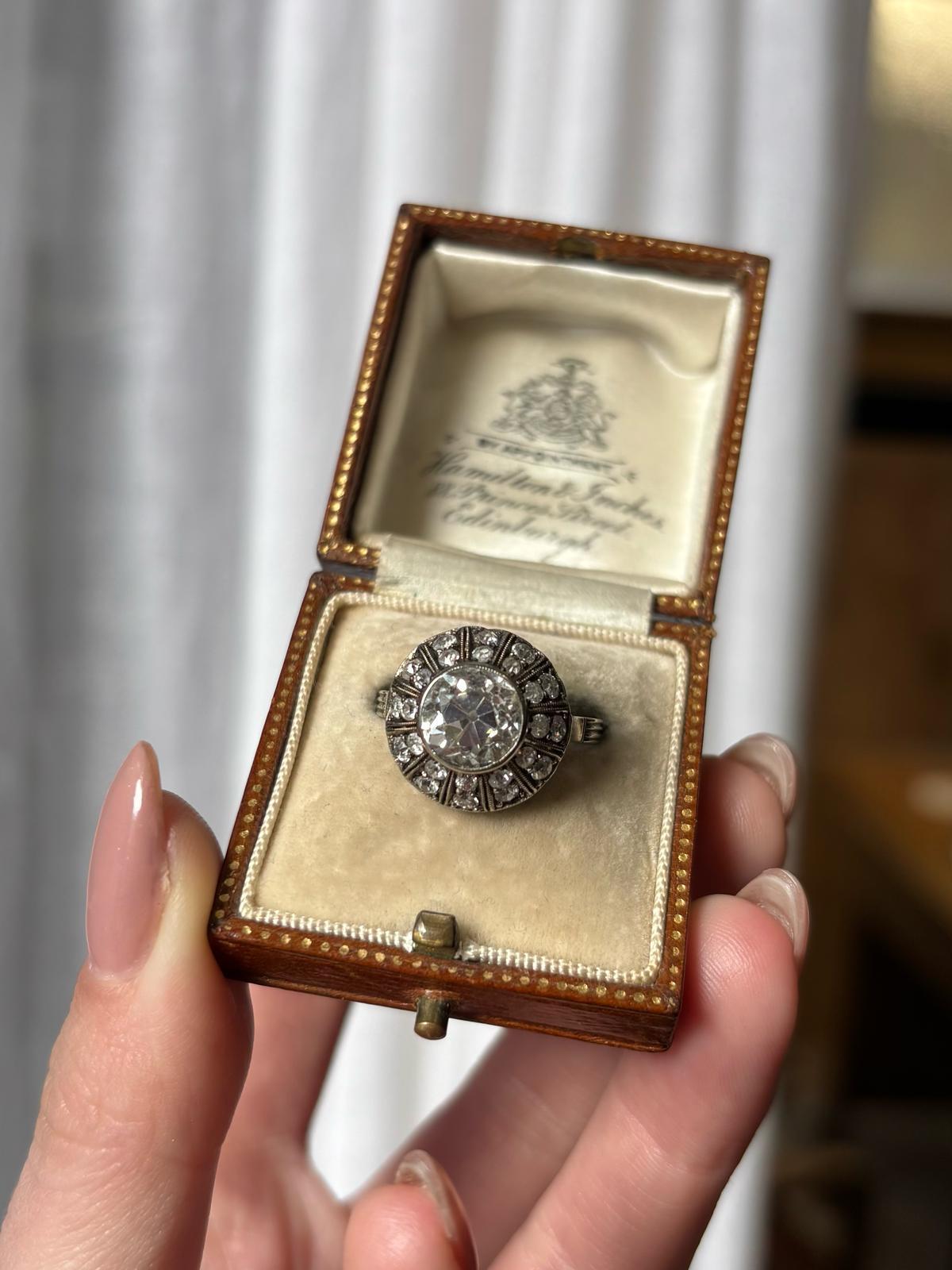 A sparkly Art Deco inspired certified old European cut diamond cluster ring in 18k white gold. 

The ring is set with a certified 2.30 carat old European cut diamond. The diamond is securely rub over set in a raised fluted cluster. There is a