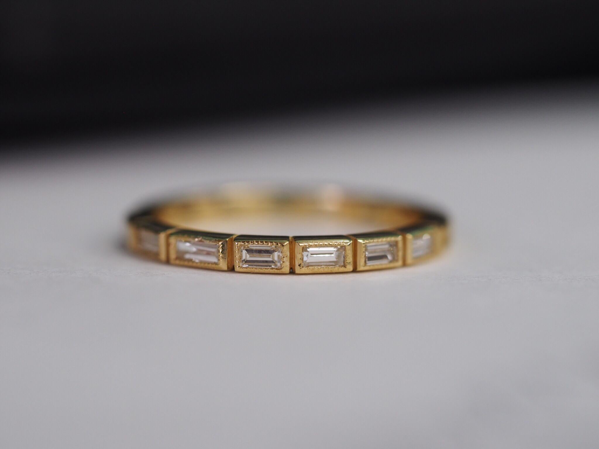 18 Karat Yellow Gold custom made eternity band with 0.61ct total weight of baguette diamonds. Each diamond is individually bezel set with a milgrain edging giving it the gorgeous ‘Art Deco’ look. Size 6.5